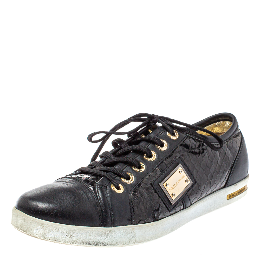 Fall in love with casual wear every time you step out in these low top sneakers from Dolce and Gabbana. Theyve been crafted from black python embossed leather and leather and styled with round toes laces on the vamps and gold tone logo plaques on the sides. The sneakers are filled with comfort and effortless style.