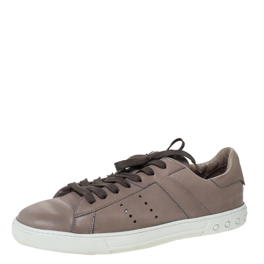 Make these stylish low top sneakers by Tod's yours this season. Crafted meticulously in Italy they are made from grey hued leather. They are styled with round toes lace up vamps perforated detailing brand logo on the counters and heels and durable rubber soles.