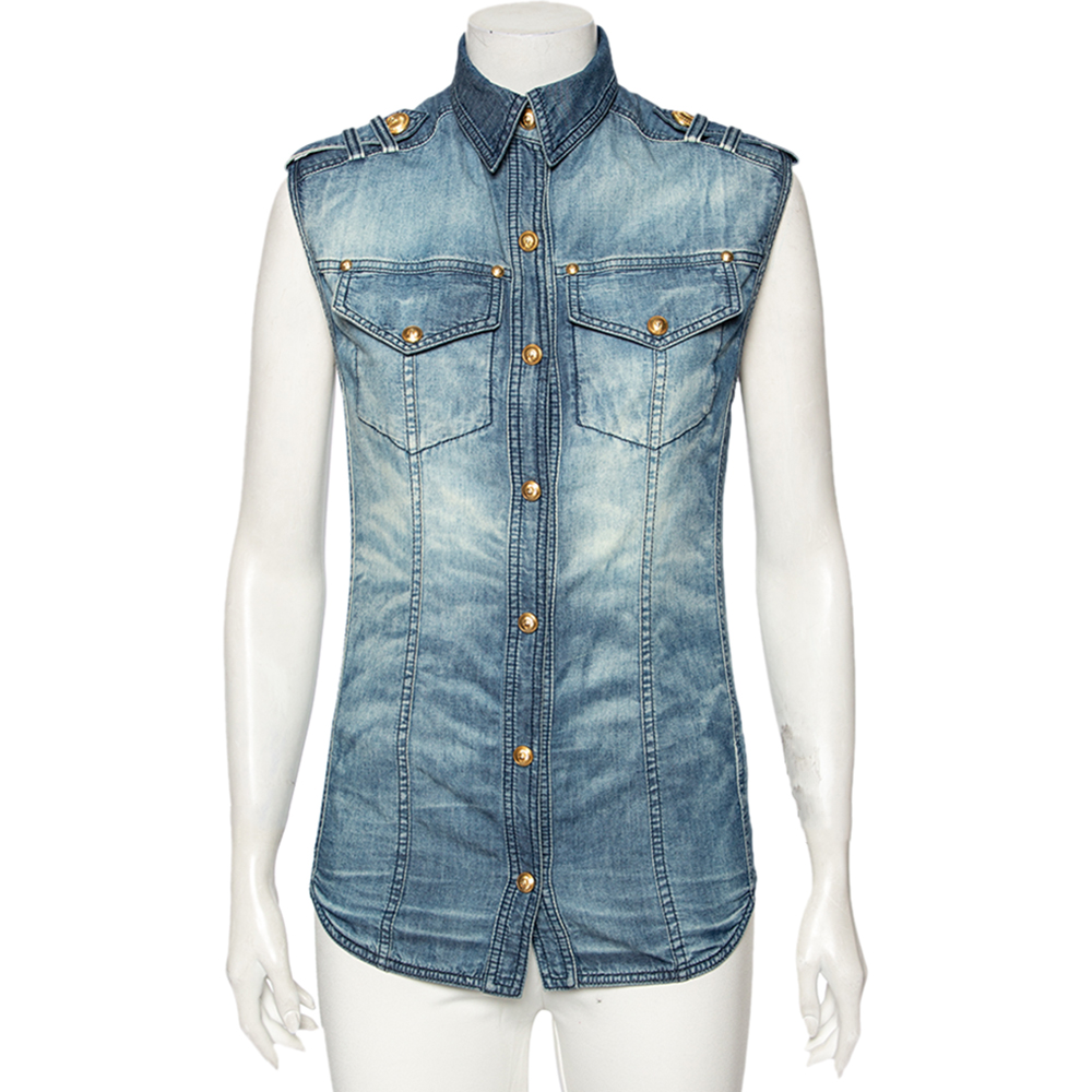 This sleeveless shirt from Balmain is perfect to add to your chic and edgy wardrobe The blue creation is made of cotton and features a faded effect. It flaunts gold tone button fastenings and sharp collars. Pair it with high waisted denims and ankle boots for a fun outing with friends.