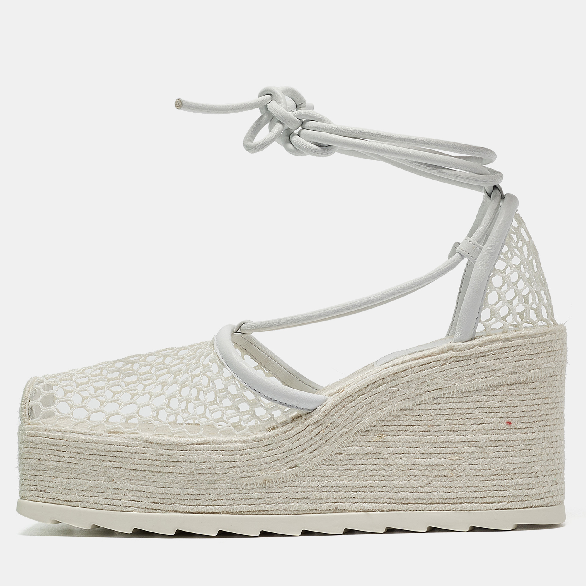 Embrace the bold craftsmanship of Bottega Venetas white mesh and leather espadrilles. These sandals feature stylish wedge platforms with charming ankle ties blending comfort with avant garde design. Perfect for those who appreciate a statement piece in their footwear collection.