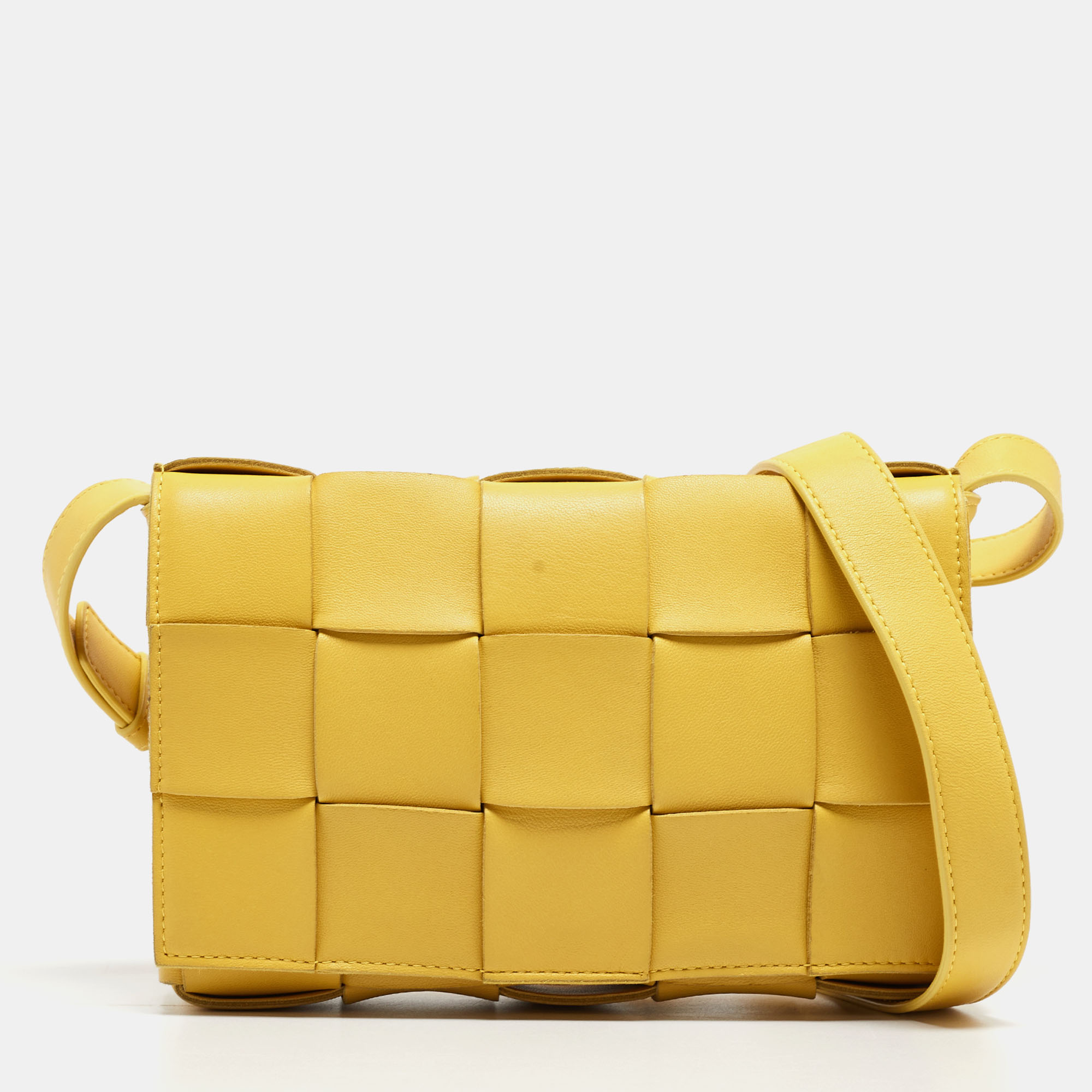 The Cassette bag by Bottega Veneta is all things stylish trendy and Instagram able. With its playful take on the brands signature house code the Intrecciato weave the bags exterior flaunts a maxi version of the weave. It is crafted from quality leather in a lovely shade of yellow. The front flap opens gracefully to a leather interior sized perfectly to carry your essentials. The bag is impeccably finished with gold tone hardware.