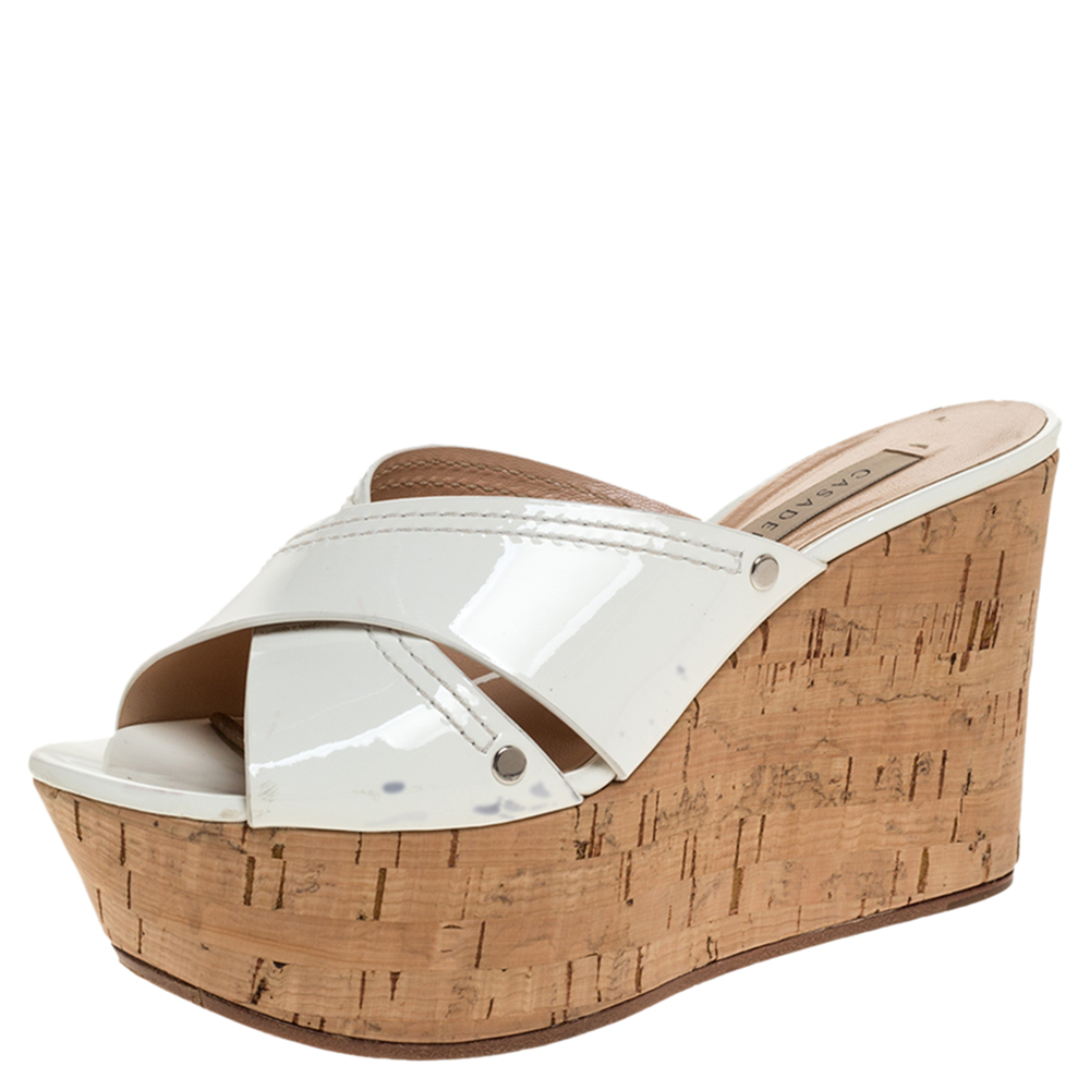 These stylish wedges come from the house of Casadei. They are crafted from patent leather in white. They are styled with open toes cross straps and 9.5 cm cork wedge heels. They are finished with durable soles.