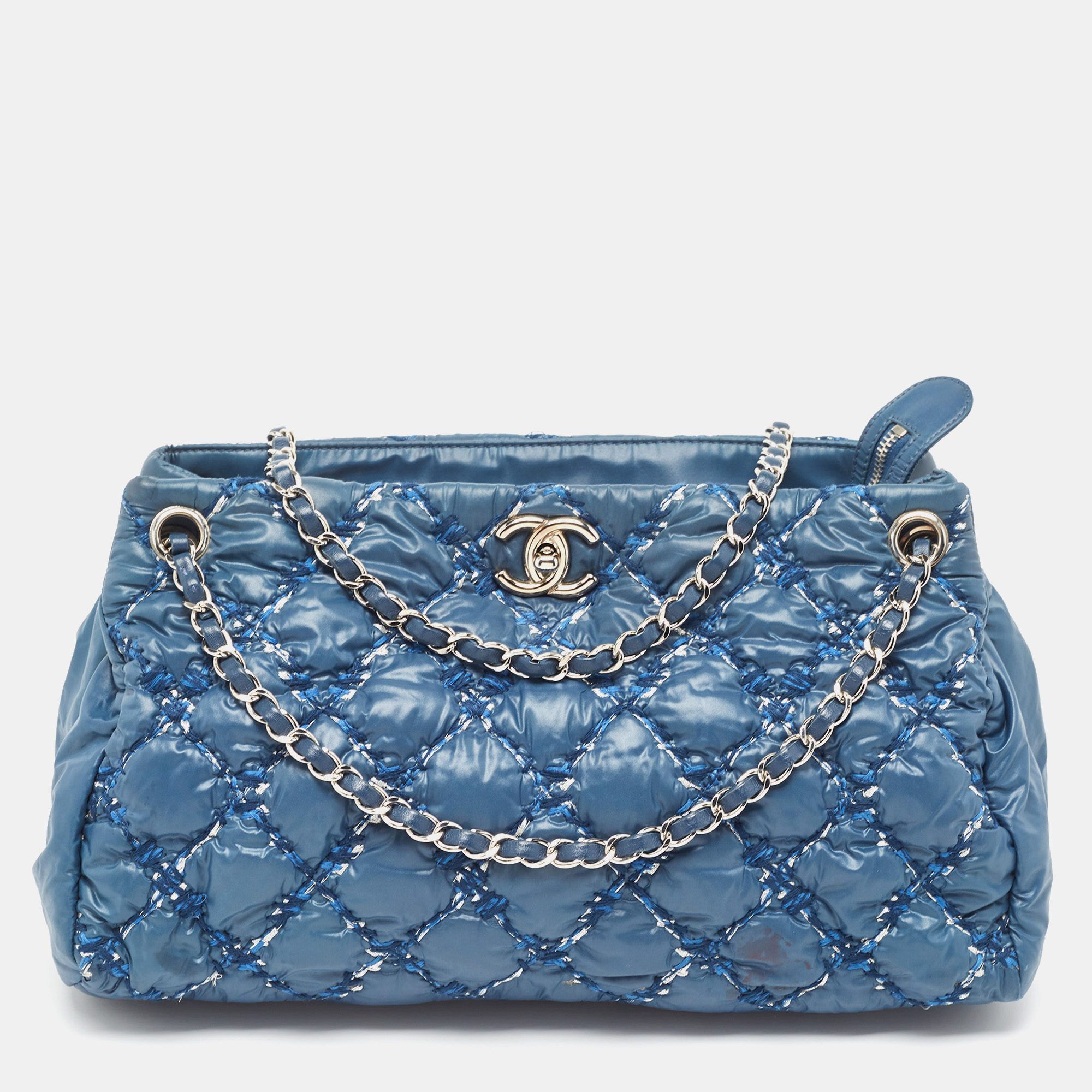 Chanel takes quilting design to the next level with this blue bubble tote that features unique stitching on the exterior to mimic the quilt design. Its so different and we love it The exterior is made of tweed and nylon giving the bag that puffy look. It also includes a chain link and a CC logo on the front.