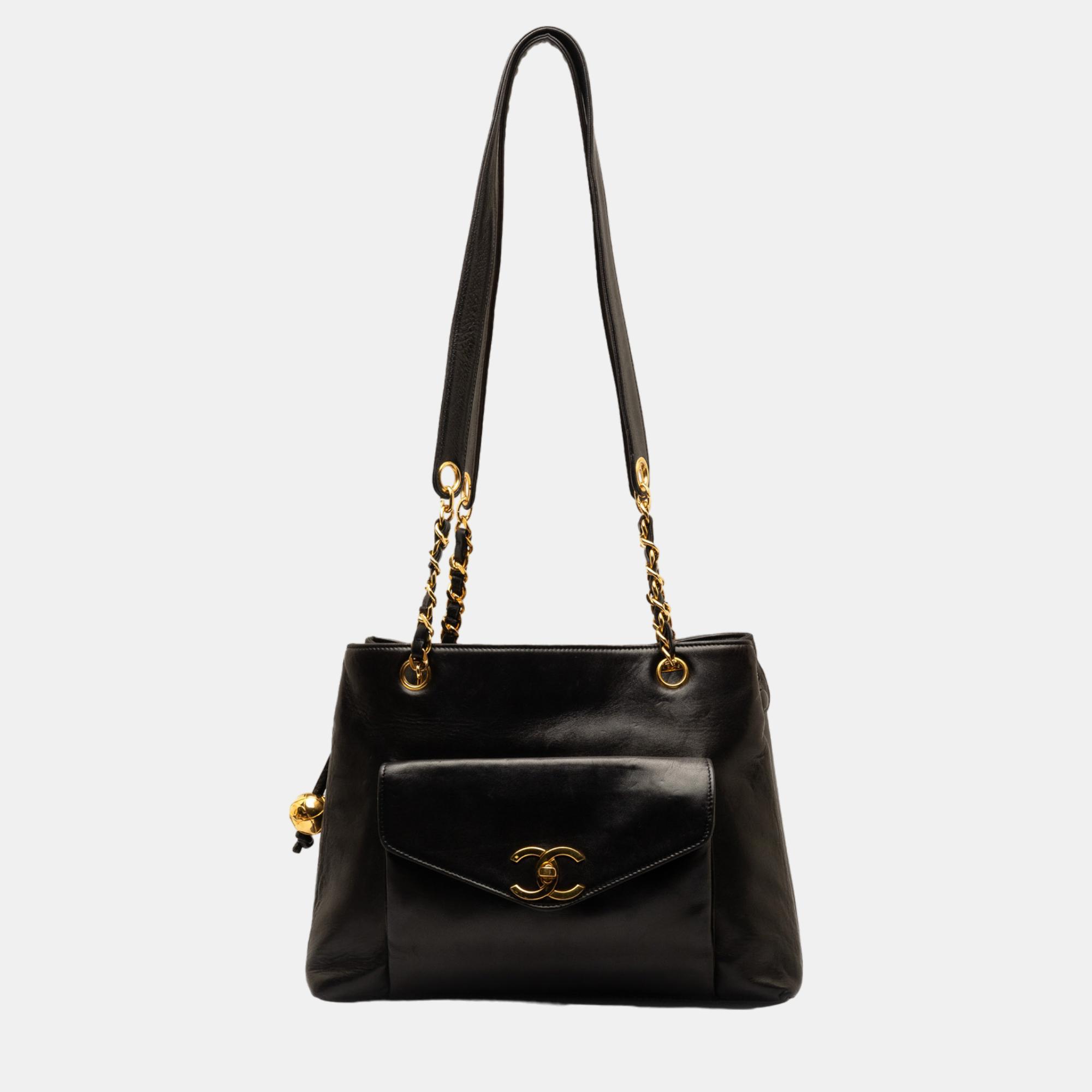 This tote bag features a lambskin leather body a curb chain strap an exterior flap pocket with turn lock closure a top zip closure and an interior zip pocket.