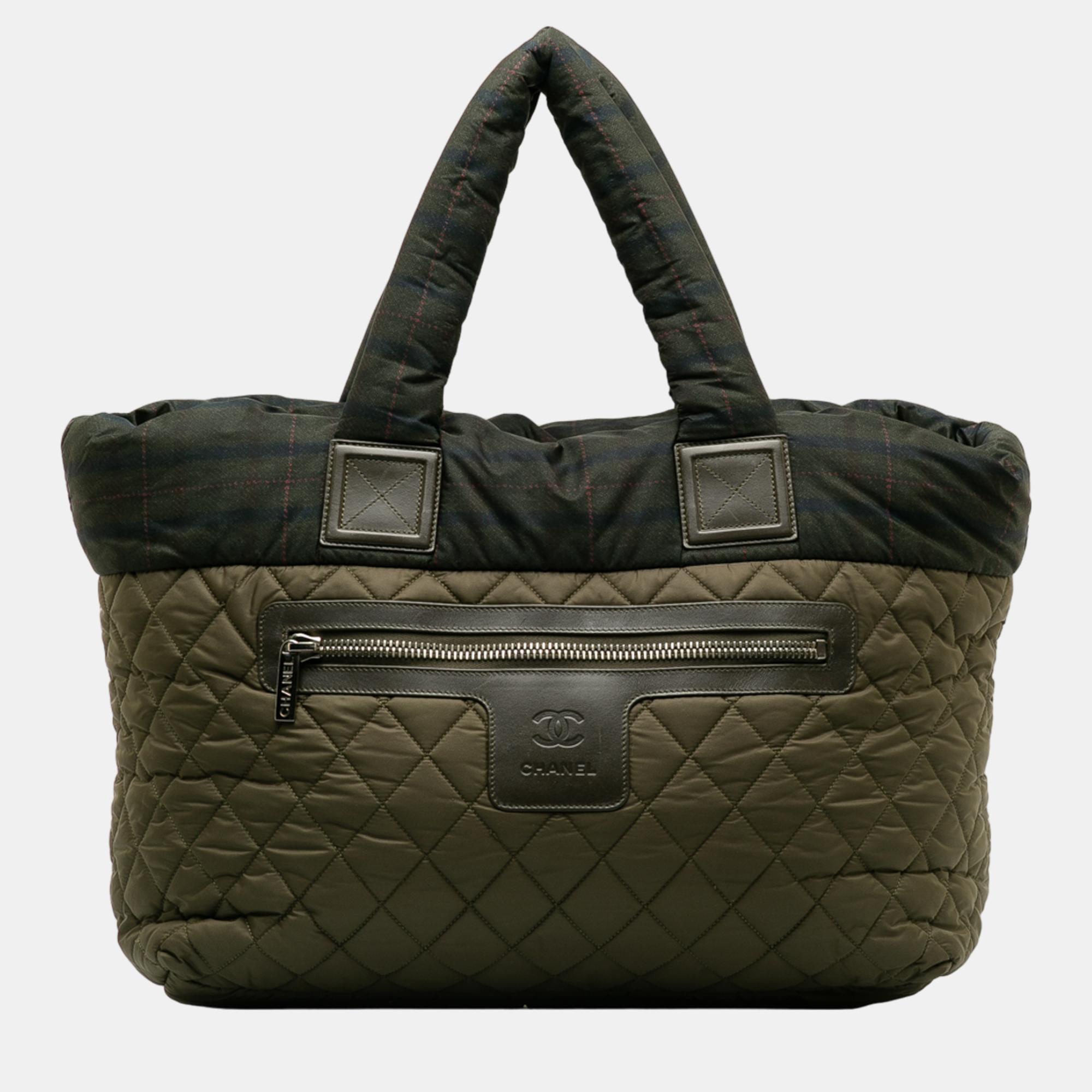 This tote bag features a quilted nylon body rolled handles a top zip closure an exterior front zip pocket and an interior zip pocket.