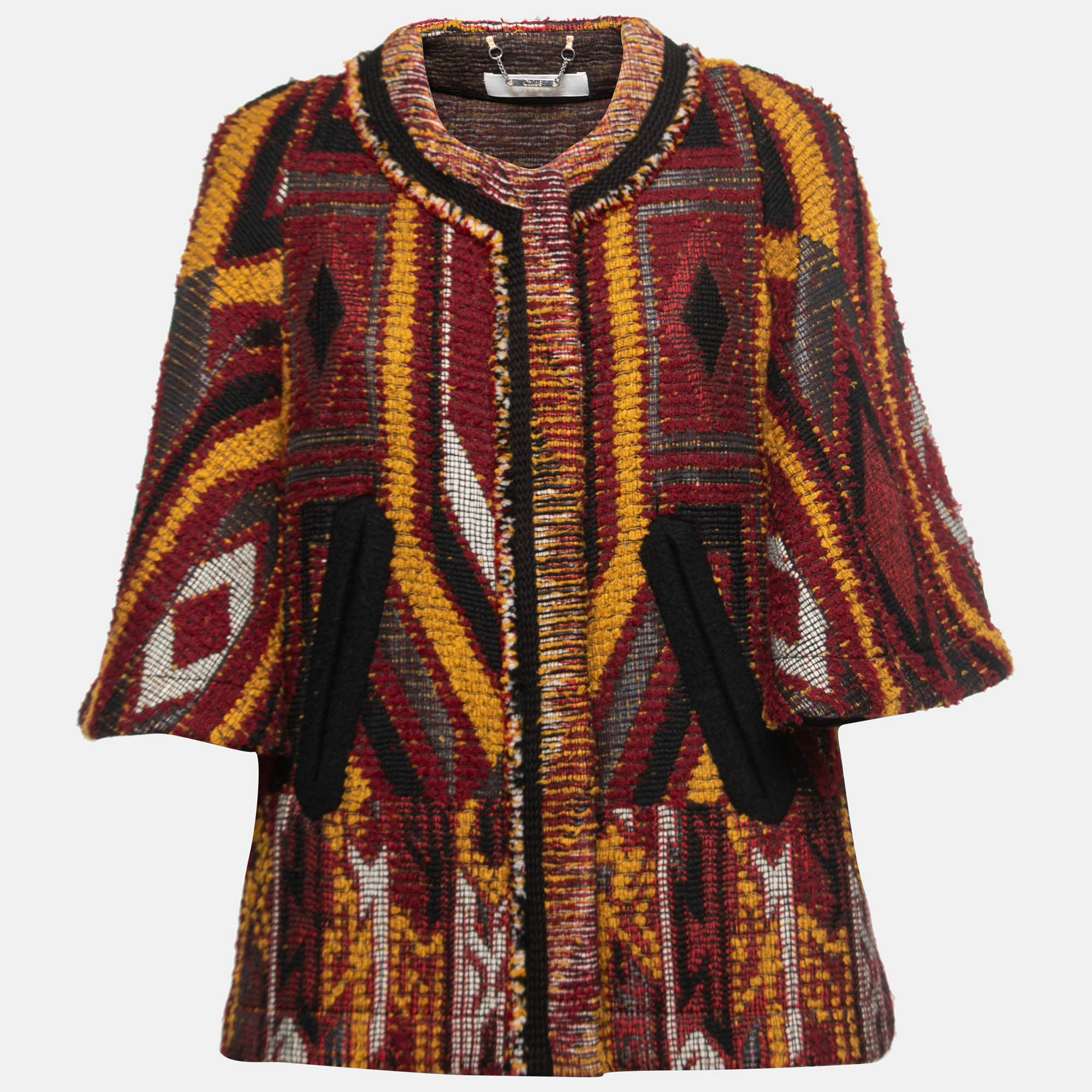The Chloé coat is a stunning outerwear piece that combines style and warmth. This cape coat features a vibrant multicolor tribal pattern woven into a textured boucle tweed fabric. With its relaxed cape silhouette and intricate design its a fashion statement for any occasion.