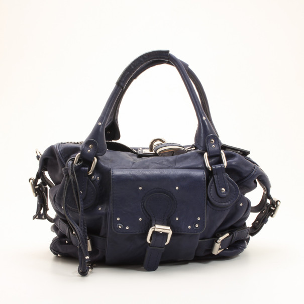 This popular and relaxed style Navy Blue Large Paddington Tote by Chloe is the ideal everyday bag. This soft blue leather Paddington will surely pair well with any casual style. It is accented with gold tone hardware and a classic Chloe inscribed padlock and key. A front buckle pocket side buckles detailing double rolled leather handles top zipper closure add the finishing touches to this handbag. The spacious interior is lined with canvas and a zipper pocket. Original Retail Price: US $1 860 Condition: Gently Used (Scuffs on corners with several scratches on hardware) Dimensions: 25 CM(H) 39 CM(W) Handle Drop: 17 CM (Distance between handle and top of the bag) Material: Leather Exterior Textile Interior Hardware: Silver tone Includes: Original Dustbag