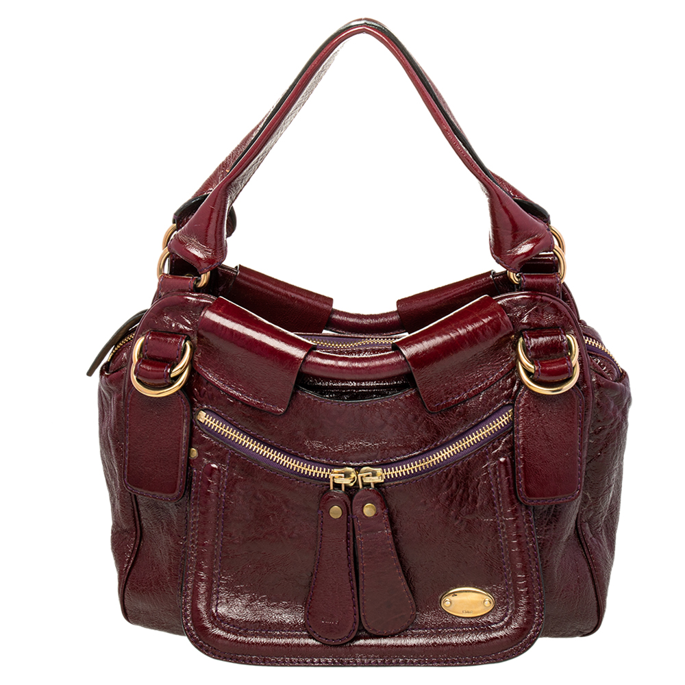 This burgundy patent leather bag is fabulously built and extremely alluring. An epitome of fashion this beautifully crafted bag comes with a highly durable fabric interior. Complement the diva in you by adorning this attractive satchel from Chloe.