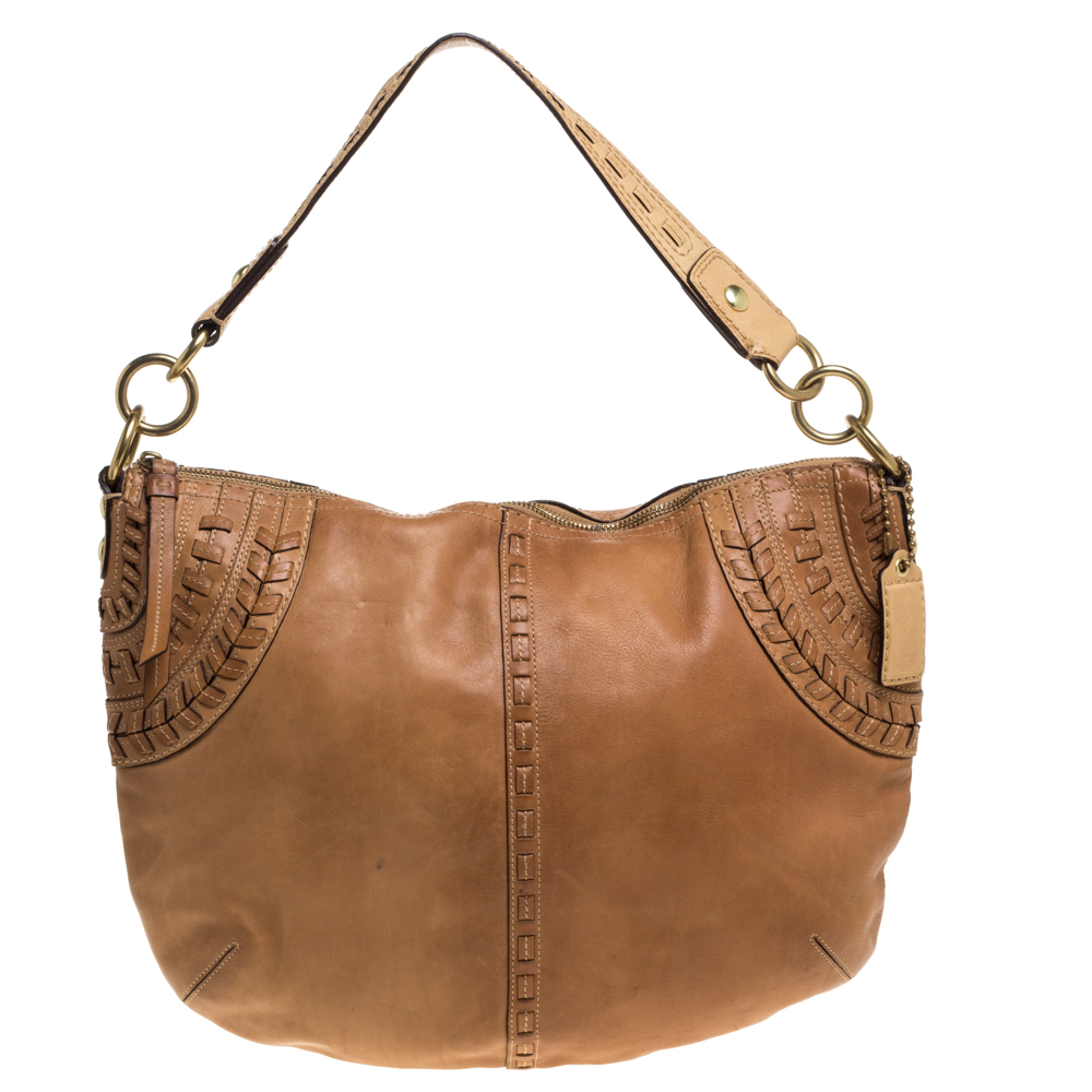 This stylish Coach hobo bag is perfect for everyday use. Crafted meticulously from quality leather it comes in a versatile shade of brown. It has a single handle stitch detailing on the exterior a zip closure that opens to a fabric lined interior with a zip pocket and the brand label. It is finished with gold tone hardware.