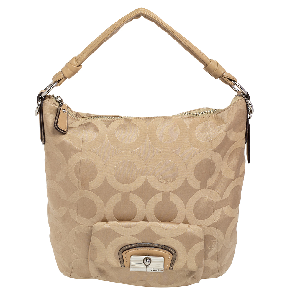 This beautifully stitched signature canvas and leather hobo is by Coach. With a capacious satin lined interior a comfortable shoulder handle and a fine finish this hobo is bound to offer style and practical ease.