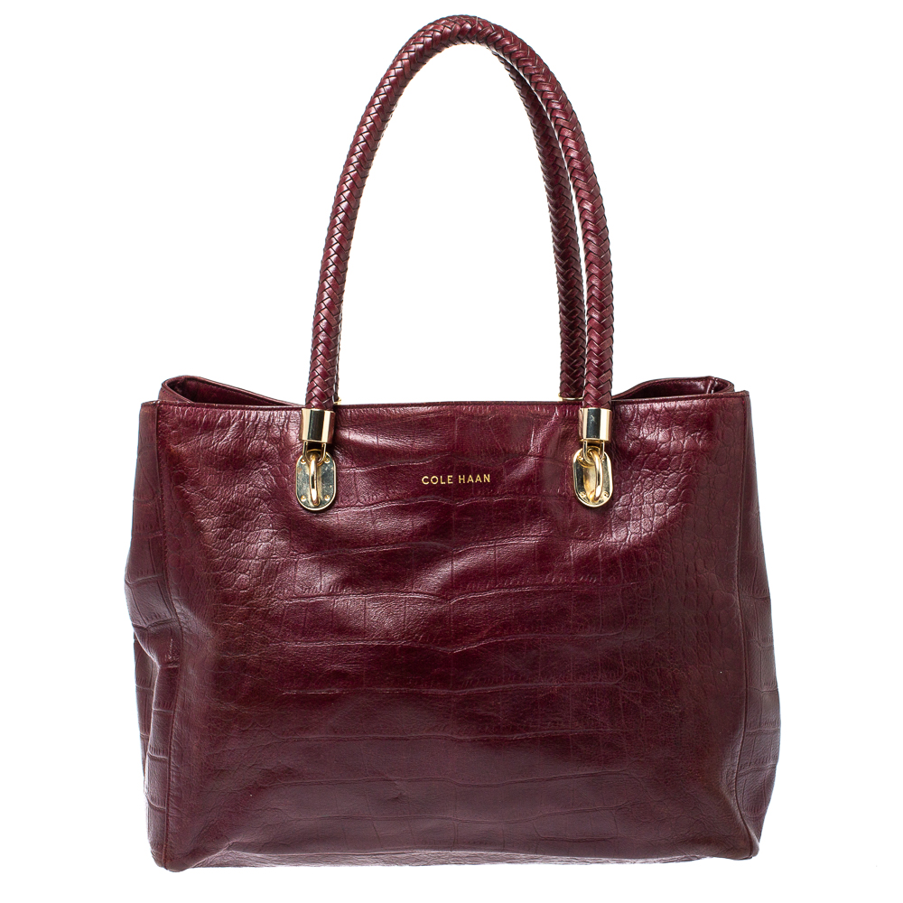 Step out to work or an evening outing with friends with this trendy Cole Haan tote. This elegant and durable handbag is made from croc embossed leather in a burgundy hue and will surely meet all your expectations. The creation is held by dual braided handles and comes equipped with a spacious satin interior which makes it ideal for daily use.