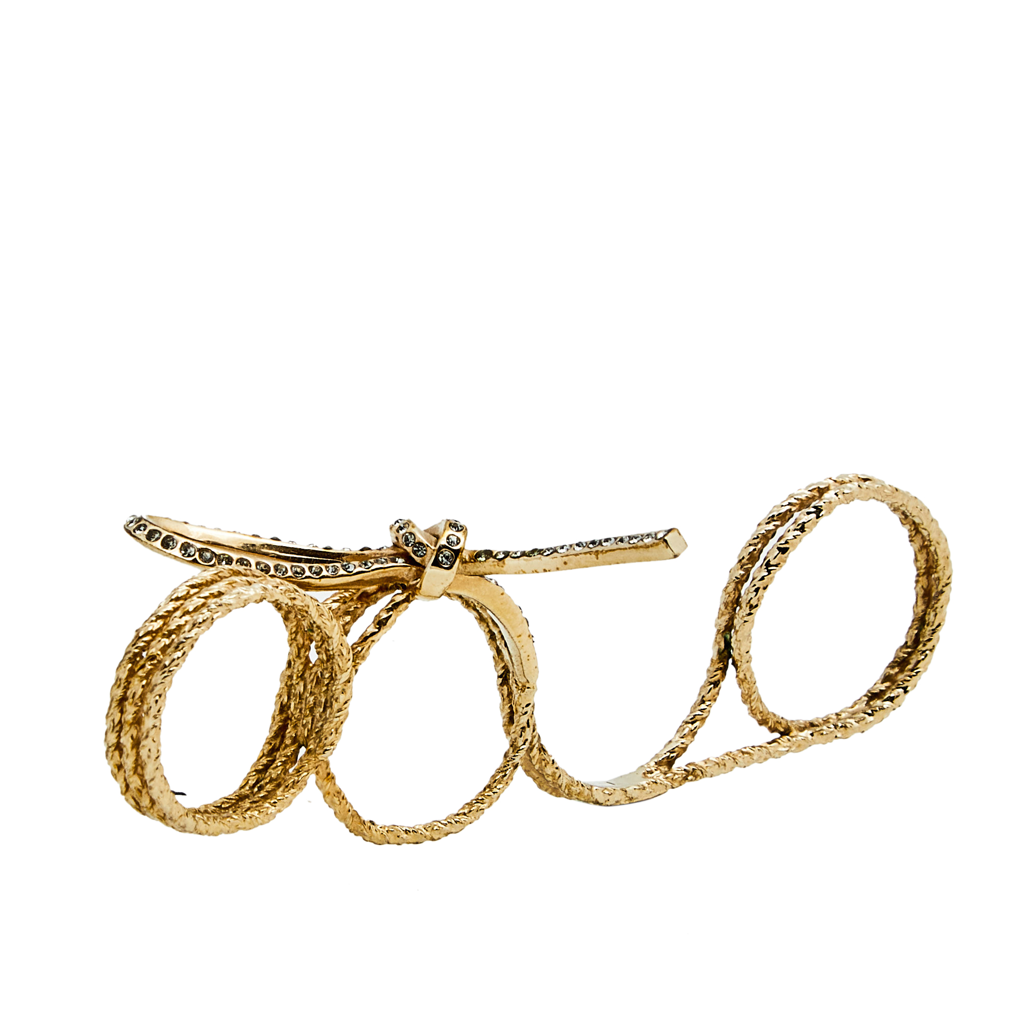 Christian Dior yet again brings a stunning ring that makes us marvel at its beauty and craftsmanship. Sculpted using gold tone metal and then shaped like a coiled thread tie the silhouette will effortlessly fit three fingers. It is topped with a rugged looking bow accented with dazzling crystals.