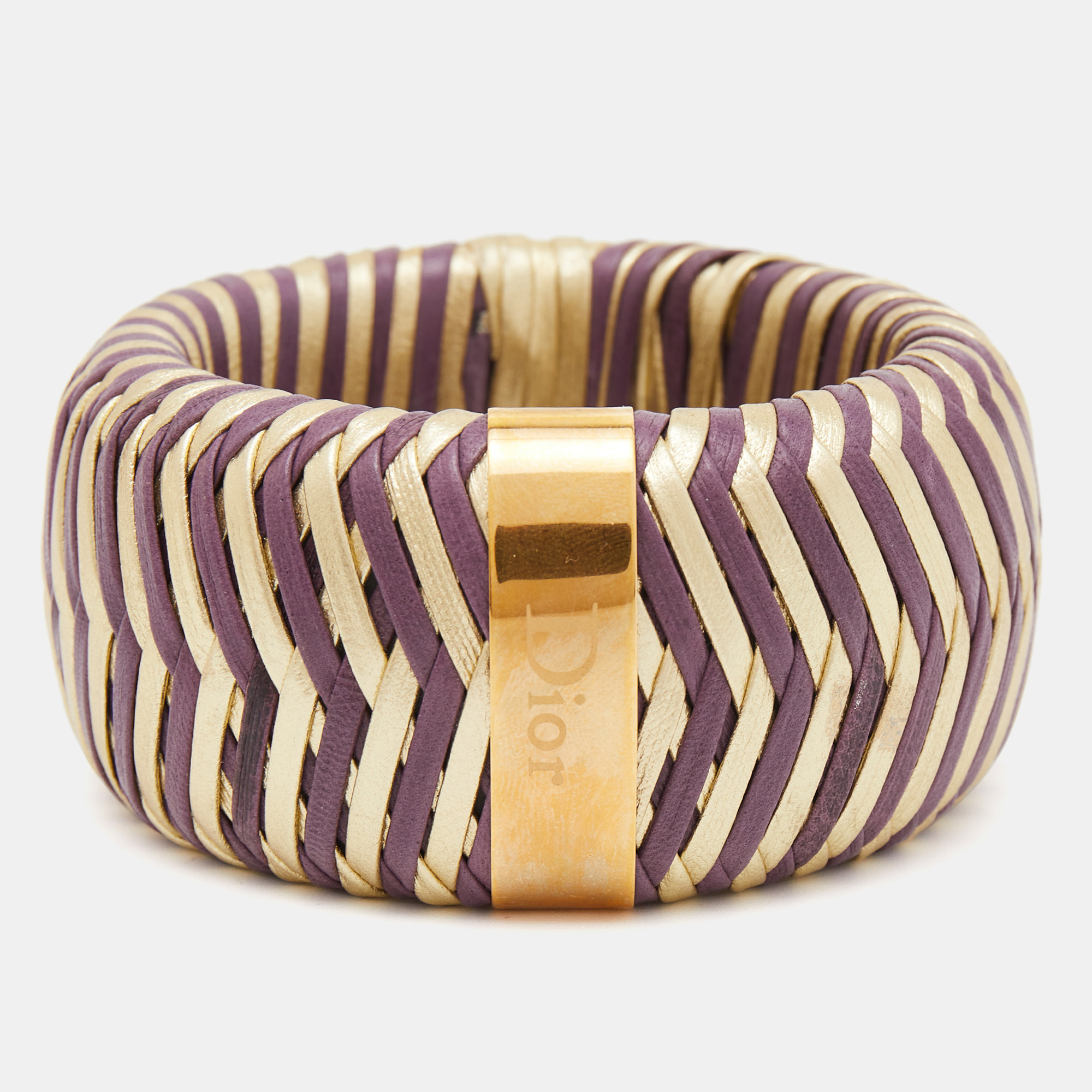 This Dior leather bracelet stands out in two colors. Made from leather it has a chevron like woven design finished with a gold tone metal accent carrying the brand name.