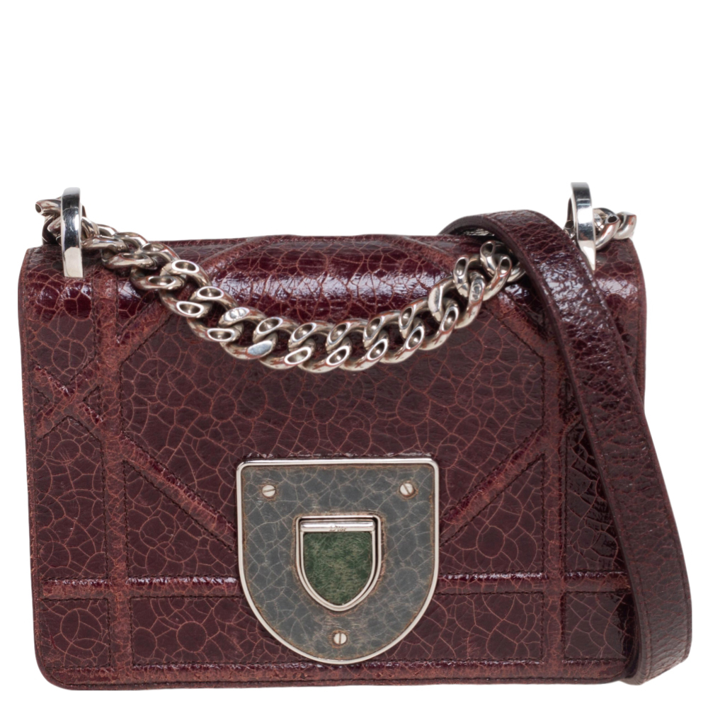 This Diorama Club shoulder bag has been crafted from burgundy leather flaunting a ceramic effect. The crest closure on the flap secures a leather interior and a shoulder chain is provided for you to carry it. You will surely love parading this beauty.