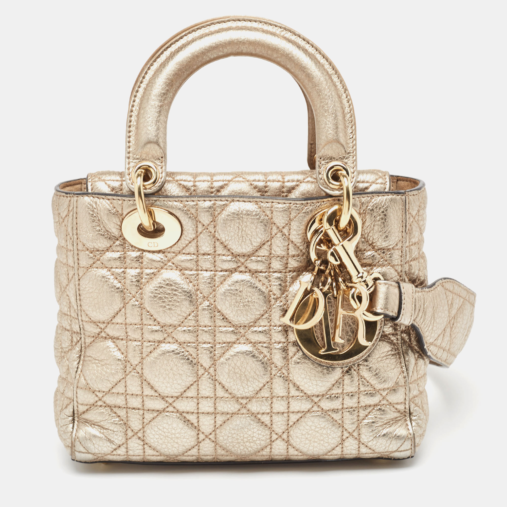 A timeless status and great design mark the Lady Dior tote. It is an iconic bag that people continue to invest in to this day. We have here this Lady Dior in gold with the iconic Cannage motif two handles and a shoulder strap.