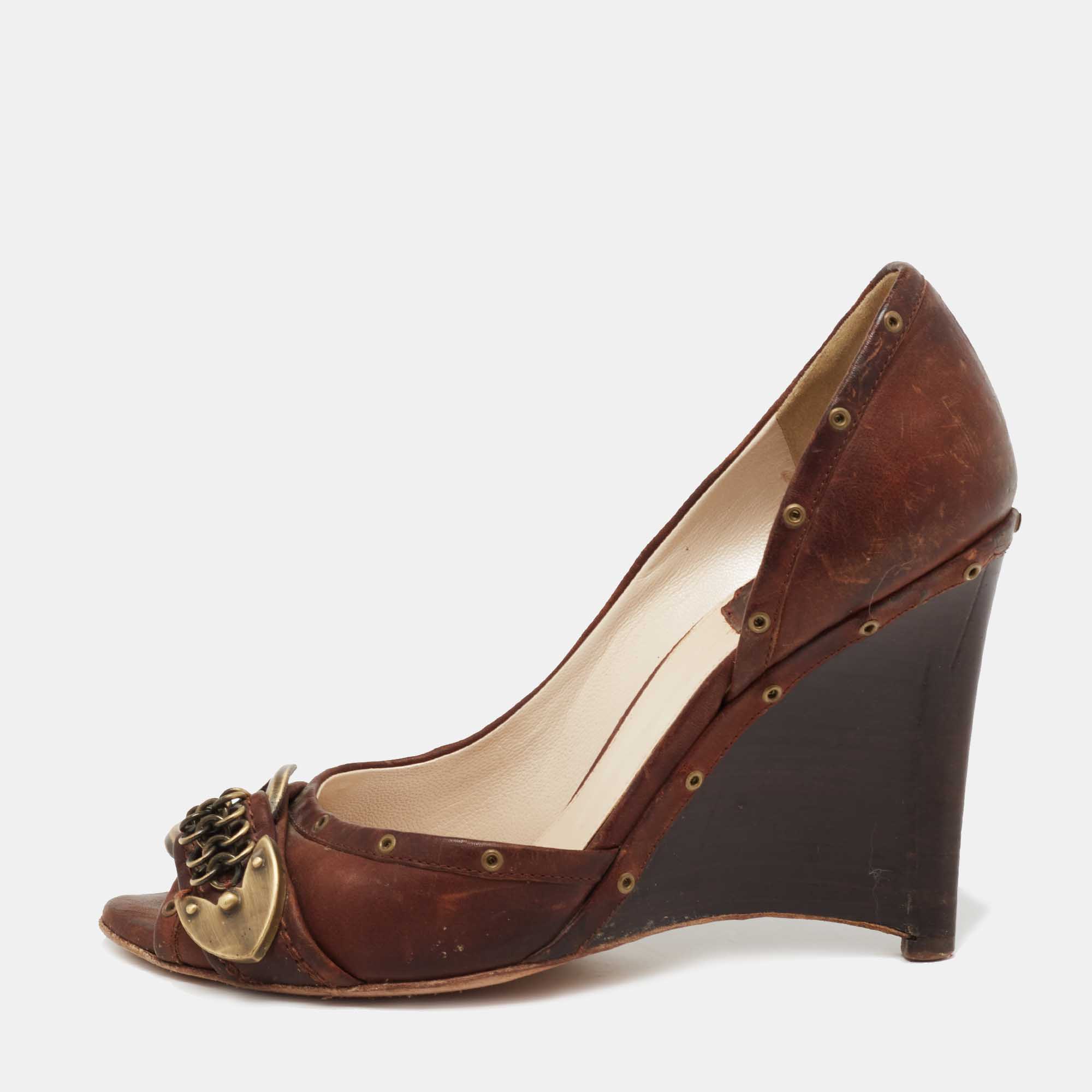 Exhibiting a chic silhouette enhanced with excellence these pumps from the House of Dior exude signatory style They are designed using brown leather on the exterior. These pumps have wedge heels peep toes and a slip on feature. Look great as you walk in these Dior pumps