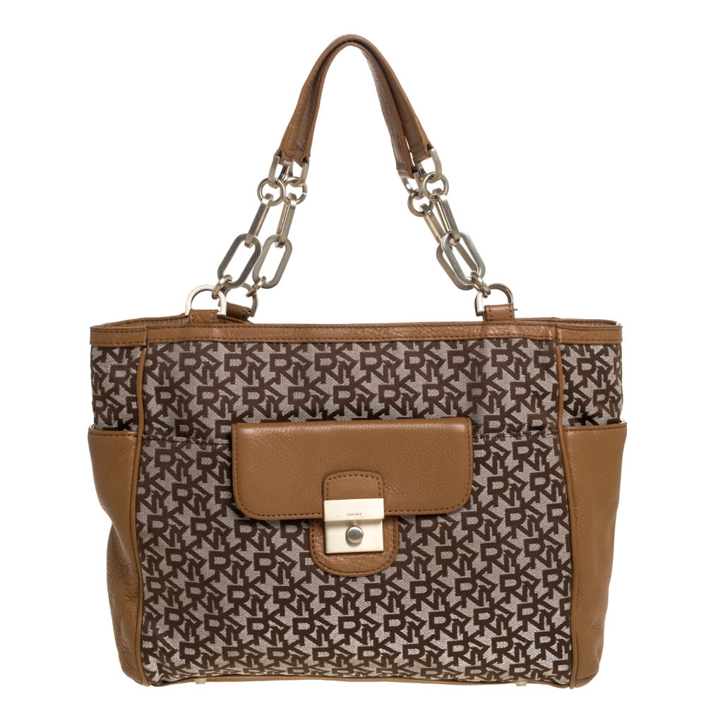 Crafted from signature printed canvas and leather this tote by Dkny is of a perfect size. Its beige and tan hued exterior is coupled with flap pocket to the front slip pockets on the sides and double handles. Lined with fabric the interior is spacious.