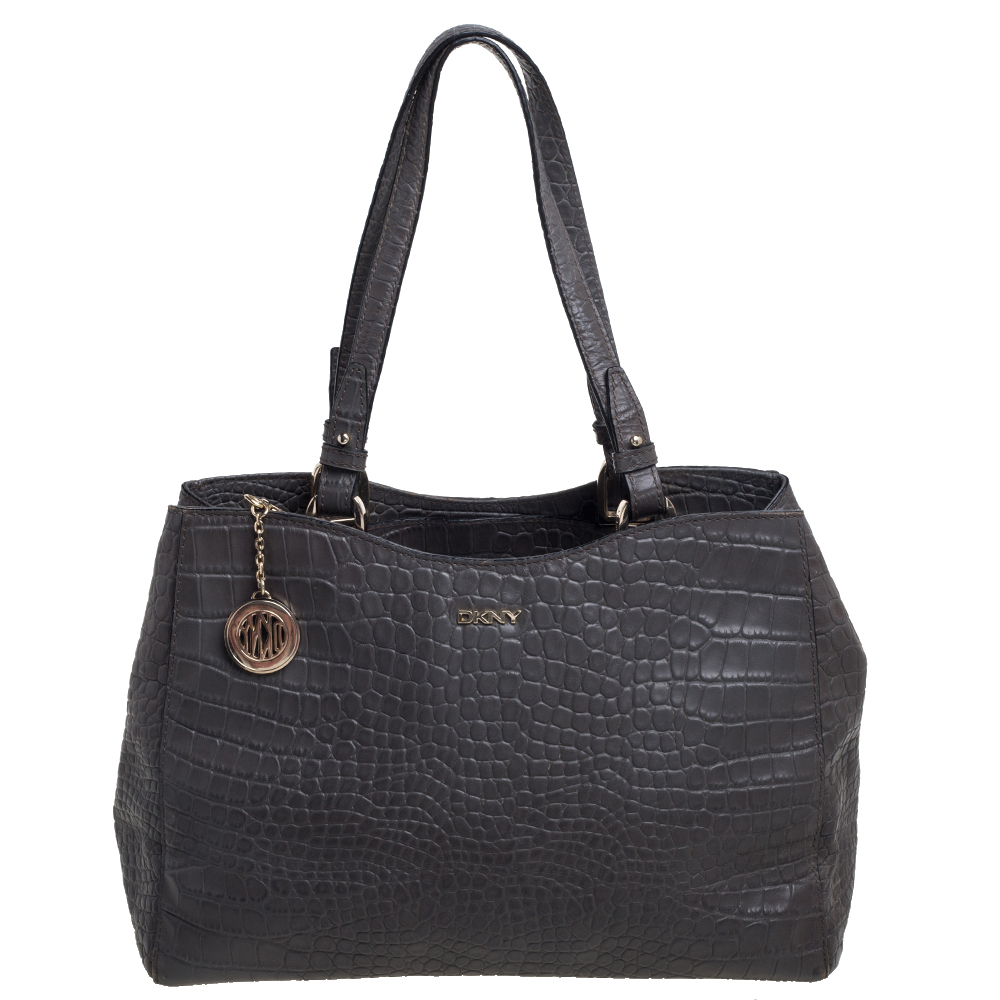 Constructed using crocodile embossed leather this DKNY tote is meant for all seasons of style and ease. The nylon lined interior of the bag is spacious and the two handles coupled with the shoulder strap add to the practicality of the grey hued tote.
