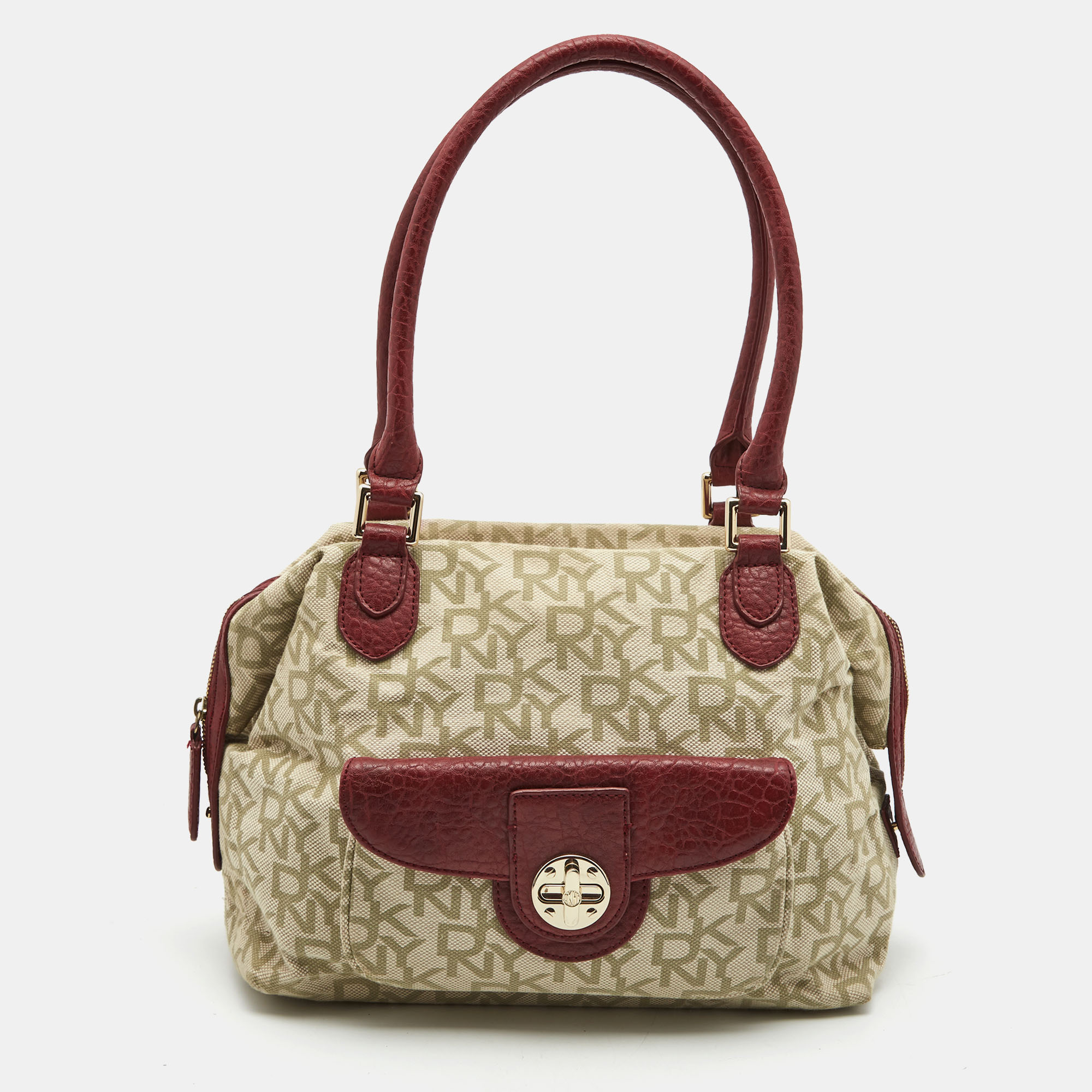 The simple silhouette and the use of monogram canvas and leather for the exterior bring out the appeal of this DKNY satchel. It features dual handles gold tone hardware and a fabric lined interior.