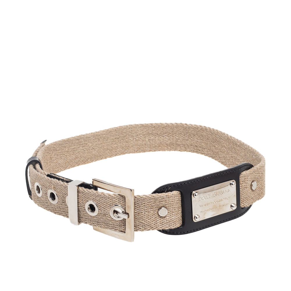 Dolce and Gabbanas beige belt is enhanced with a metal logo plaque that depicts the brands signature reflecting the house's play on branding. It's expertly crafted in canvas with a silver tone pin buckle at the center.