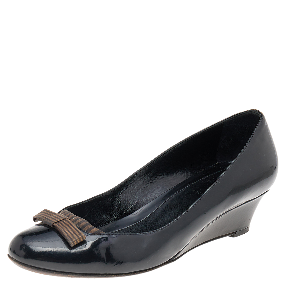 Youre choosing comfortable style with this pair of patent leather pumps. The Fendi pumps feature covered toes low wedge heels and bow detailing. Don these pumps and enjoy all day ease.