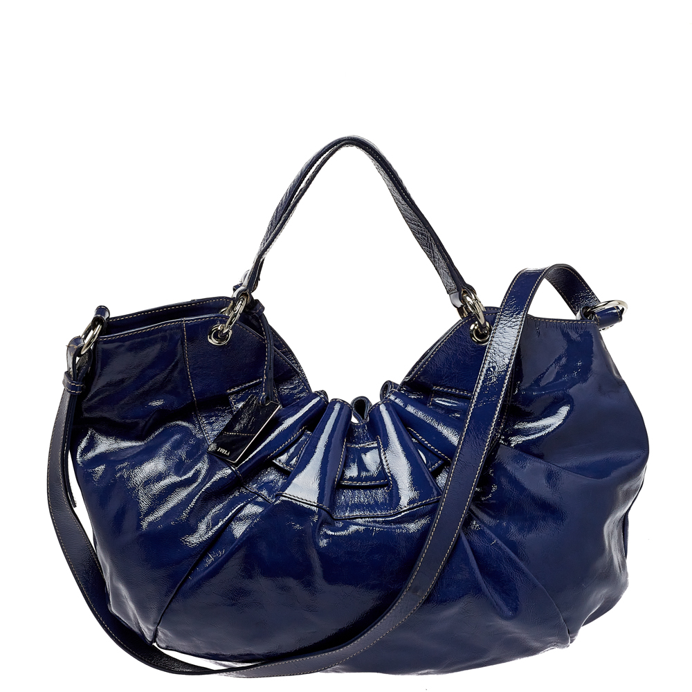 Furlas Ninfea hobo is a spacious bag with a gathered top design. This here is crafted using blue patent leather and styled with two handles a shoulder strap and a fabric lined interior.