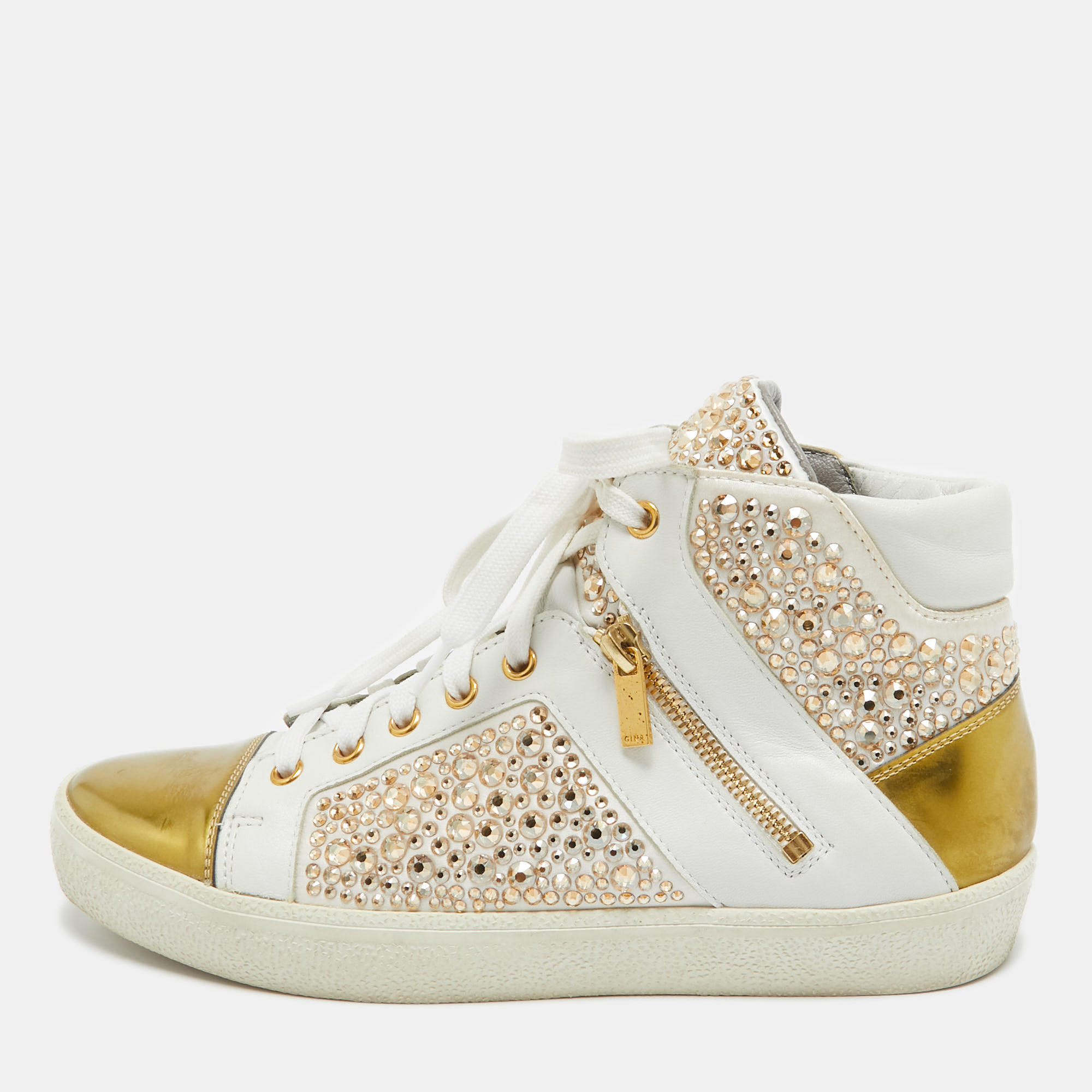 A little bit of flash could be truly modish and so are these high top sneakers by Gina. These have been crafted in white leather with golden trims and feature strass embellishment in gold tone all over. Insoles are leather lined.