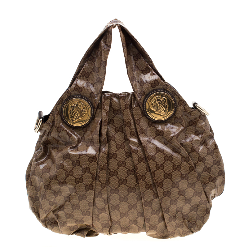 This Gucci hobo is built for everyday use. Crafted from GG crystal canvas it has a brown exterior and two handles for you to easily parade it. The nylon insides are sized well and the Hysteria hobo is complete with the signature emblems in gold tone hardware.