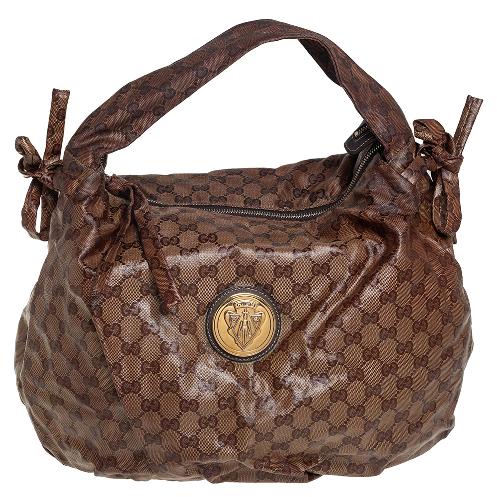 This Gucci hobo is built for everyday use. Crafted from GG Crystal coated canvas it has a beige exterior and a single handle for you to easily parade it. The fabric insides are sized well and the hobo is complete with the signature emblems.