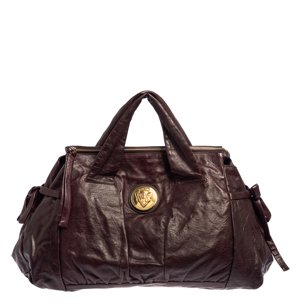 This Gucci Hysteria bag is built for everyday use. Crafted in Italy it is made from leather and comes in a burgundy hue. It has ties on the sides and dual handles for you to parade it. The nylon interior is spacious and is secured with zip closure. The tote bag is complete with the signature emblem on the front.