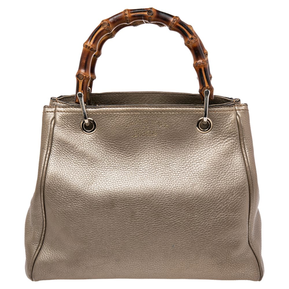 Handbags as fabulous as this one are hard to come by. So own this gorgeous Gucci tote today and light up your closet Crafted from metallic gold leather this stunning number has a spacious canvas interior and is wonderfully held by two bamboo handles which make the piece all the more worthy of being in your closet.