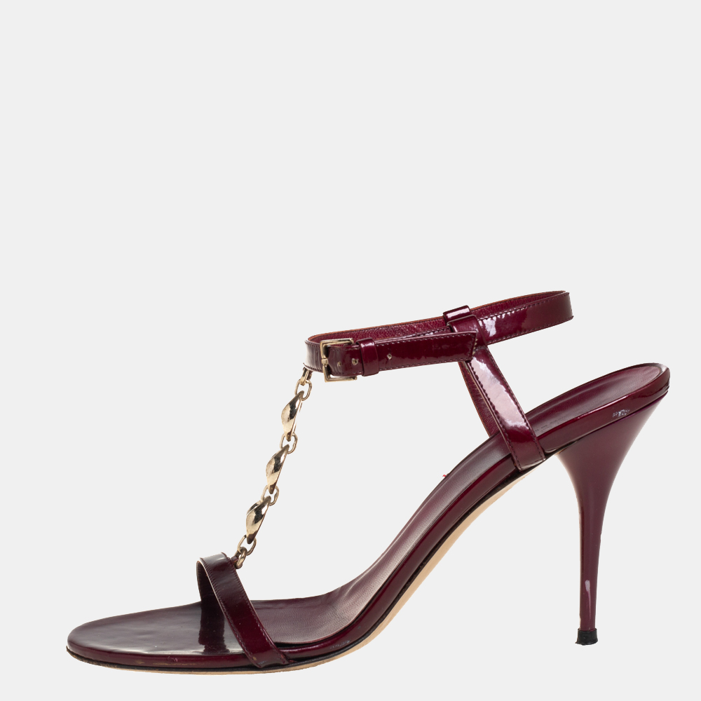 How can one not fall in love with these stunning sandals by Gucci Theyve been beautifully crafted from maroon patent leather and styled with gold tone chain T straps on the vamps. The sandals carry open toes ankle straps with buckle fastening and 10 cm heels.