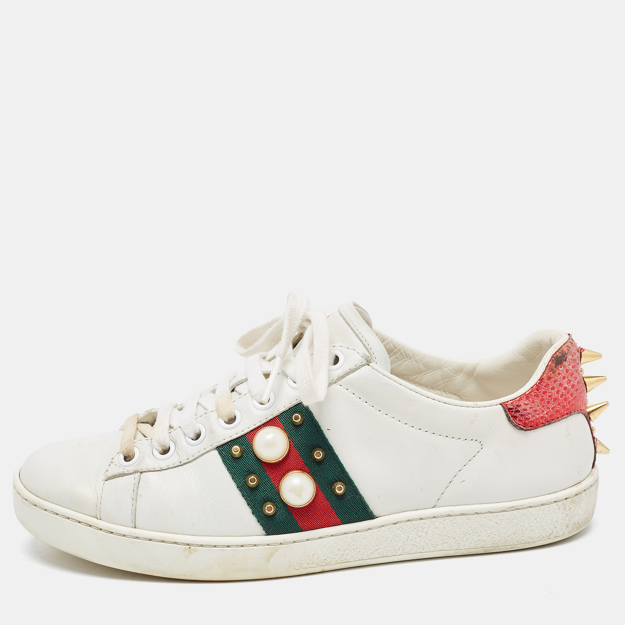 Stacked with signature details this Gucci pair is rendered in leather and is designed in a low cut style. The sneakers are fashioned with lace ups on the uppers the iconic web stripe with faux pearls and studs on the sides and faux pearl embellishments.