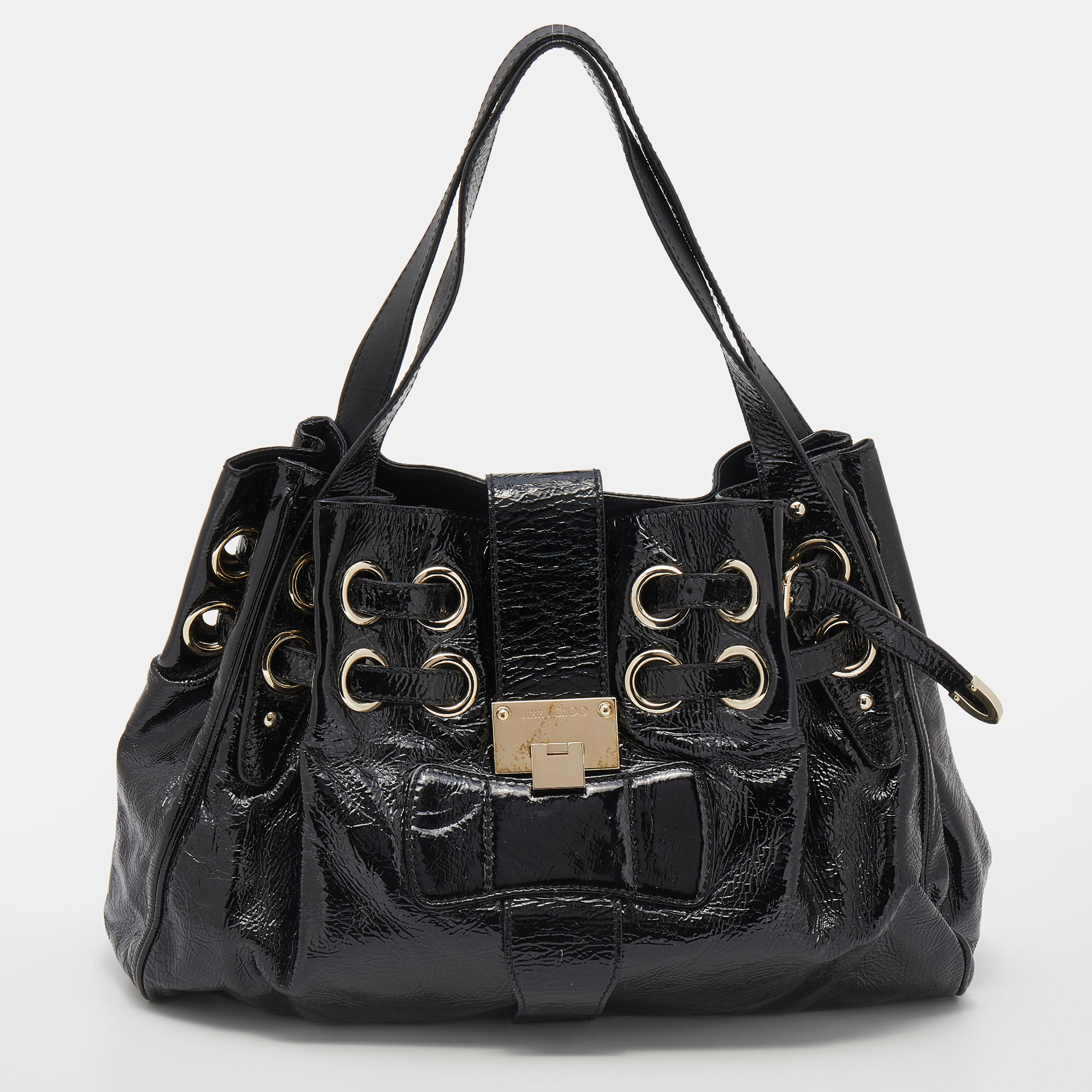 One of the most stunning creations from the House of Jimmy Choo is this Riki tote bag. It is made from black crinkled patent leather on the exterior. It features an Alcantara lined interior and gold tone hardware. The slightly slouched silhouette of the tote is supported by dual handles.