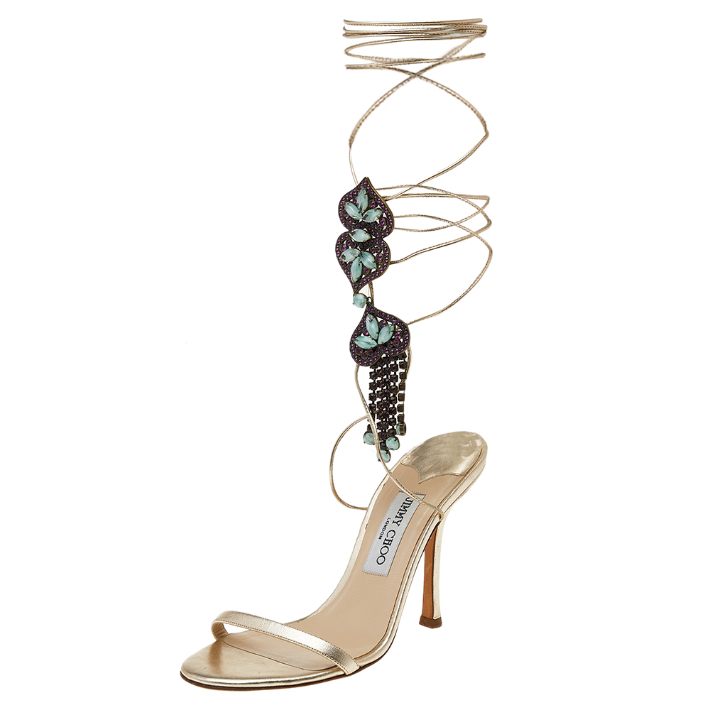 The right pair of shoes does not only make a woman look fabulous but also gives her confidence. These Jimmy Choo sandals made from leather carry elegance and wonder in their design of metallic beige vamp straps ankle wraps embellishments and 10.5 cm heels.