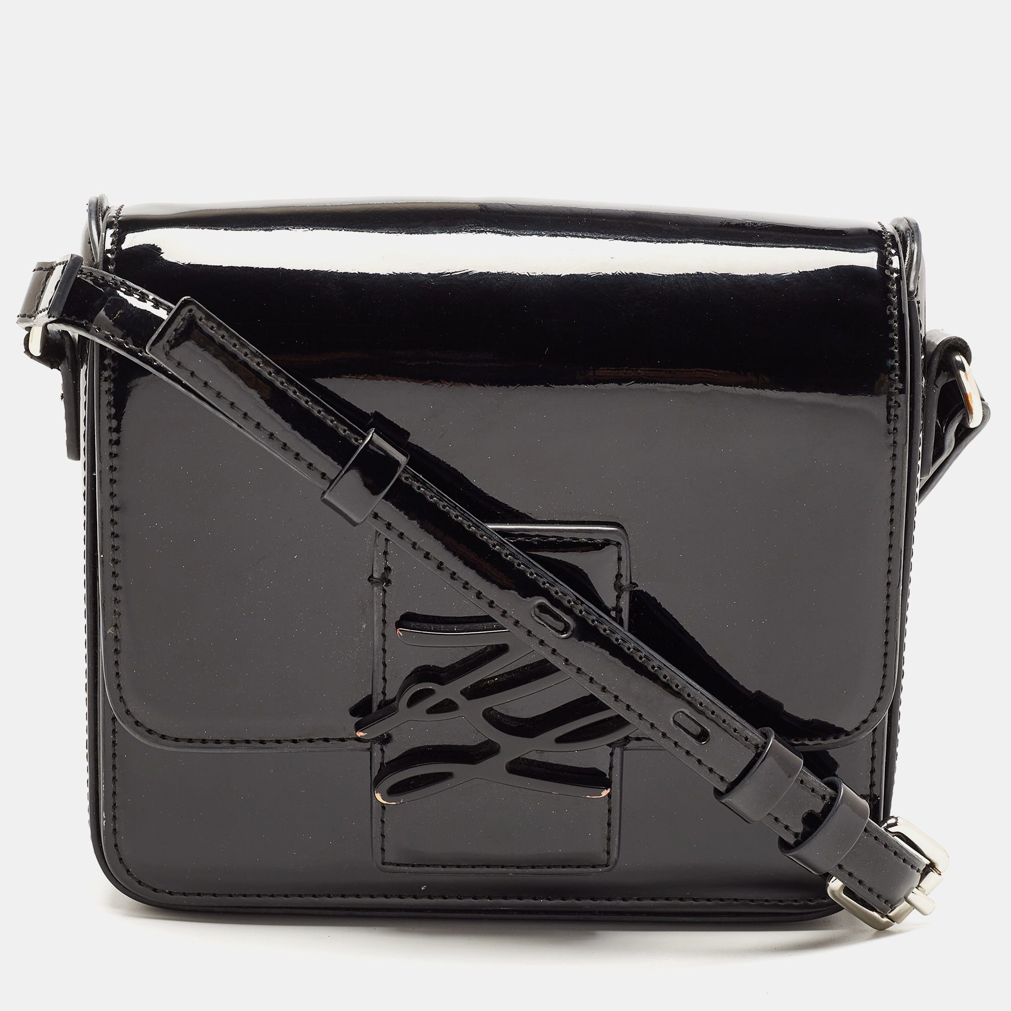 This Karl Lagerfeld bag will uplift your style quotient and take it a notch higher. Crafted from black hued patent leather it features the brand logo in the front. It is styled with a shoulder strap silver tone hardware and a fabric lined interior.