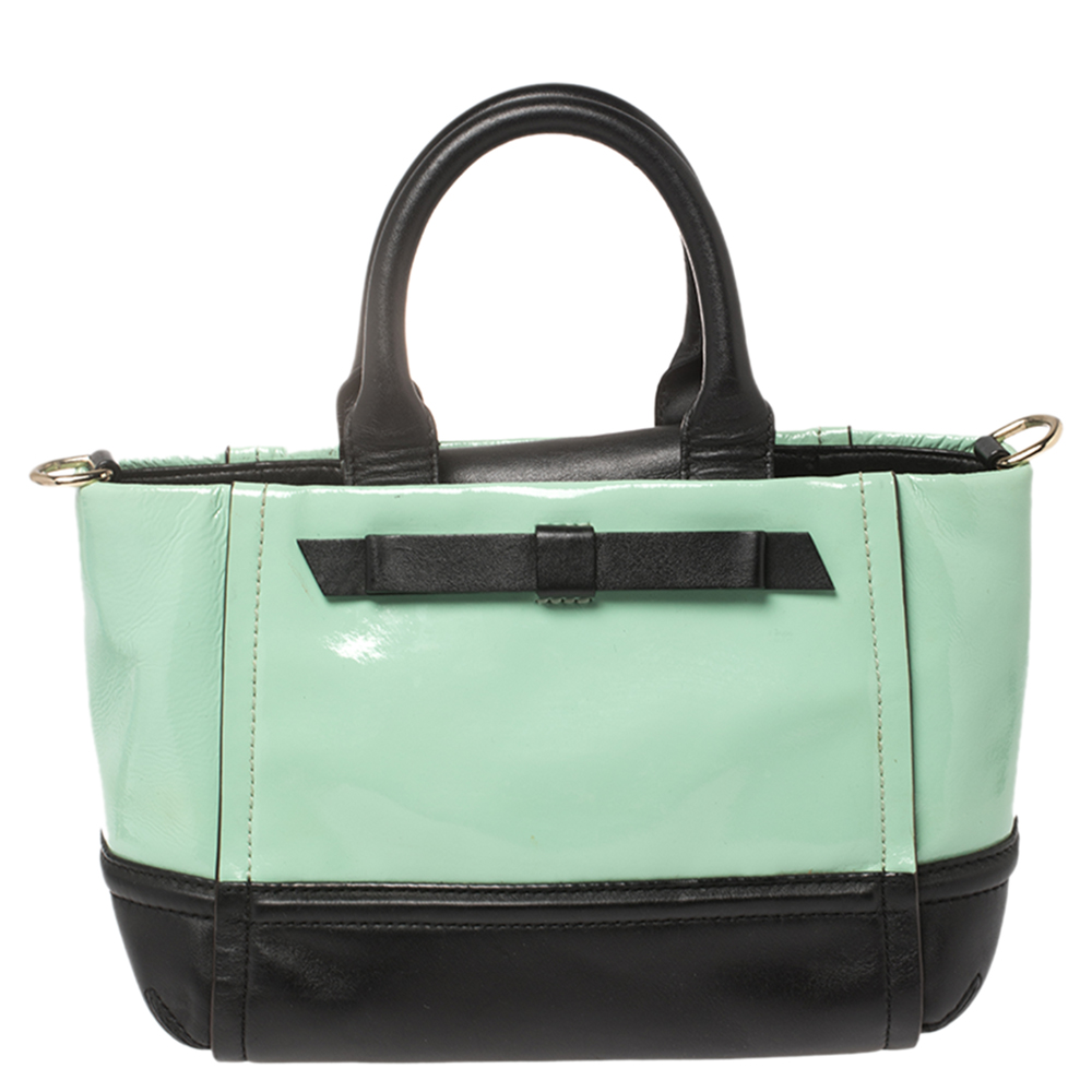 This easy to carry Kate Spade tote can be carried from office to brunches. The bag is made from mint green patent leather as well as black leather and it is elegantly held by two top handles and a shoulder strap. It is complete with a bow at the front and the brand plaque at the back.