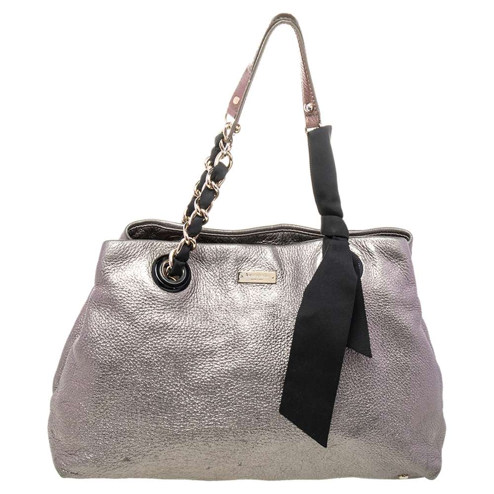 Kate Spade brings you this gorgeous bag that carries a fabulous design. It flaunts a silver hue with a leather exterior a spacious canvas interior and two top handles. it is complete with the brand label at the front.