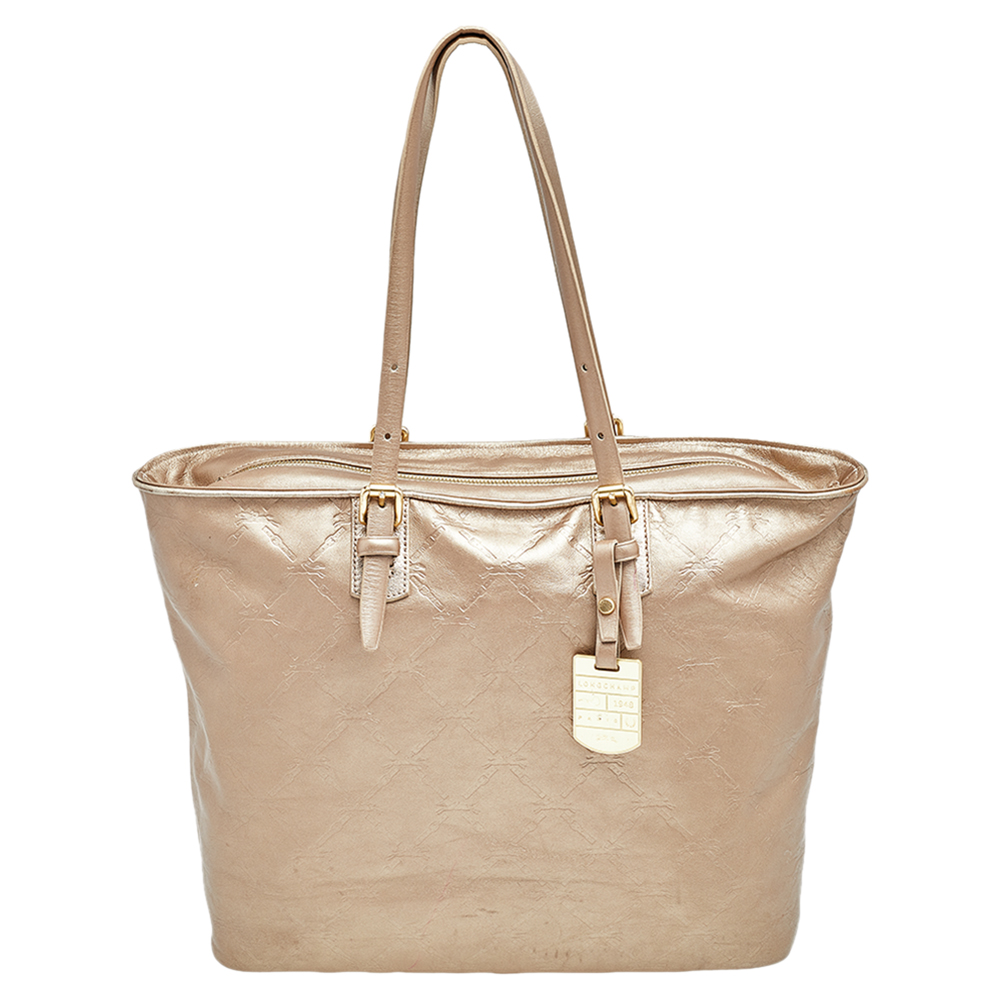 Take your everyday essentials with you in this stylish LM Cuir shopping tote from Longchamp. It has been made from gold leather and comes created in a sturdy shape and design. It is designed with gold toned hardware and has dual handles.