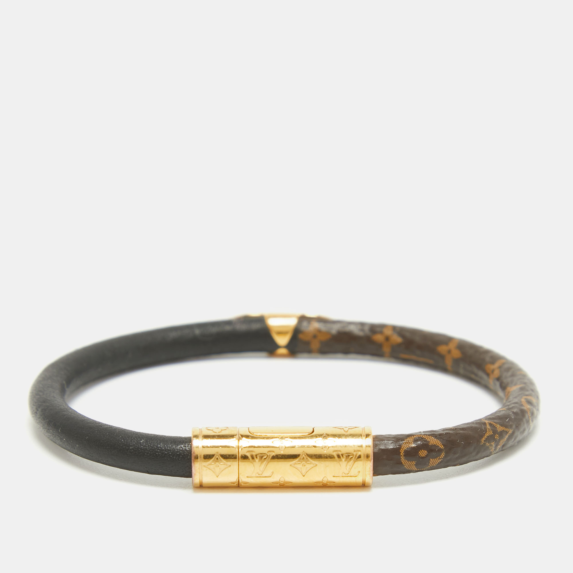 This Louis Vuitton creation is a unique charm to uplift your style made from the combination of signature monogram canvas and black leather. This Daily Confidential bracelet is designed with gold tone metal inserts and features signature symbols for a fine finish.