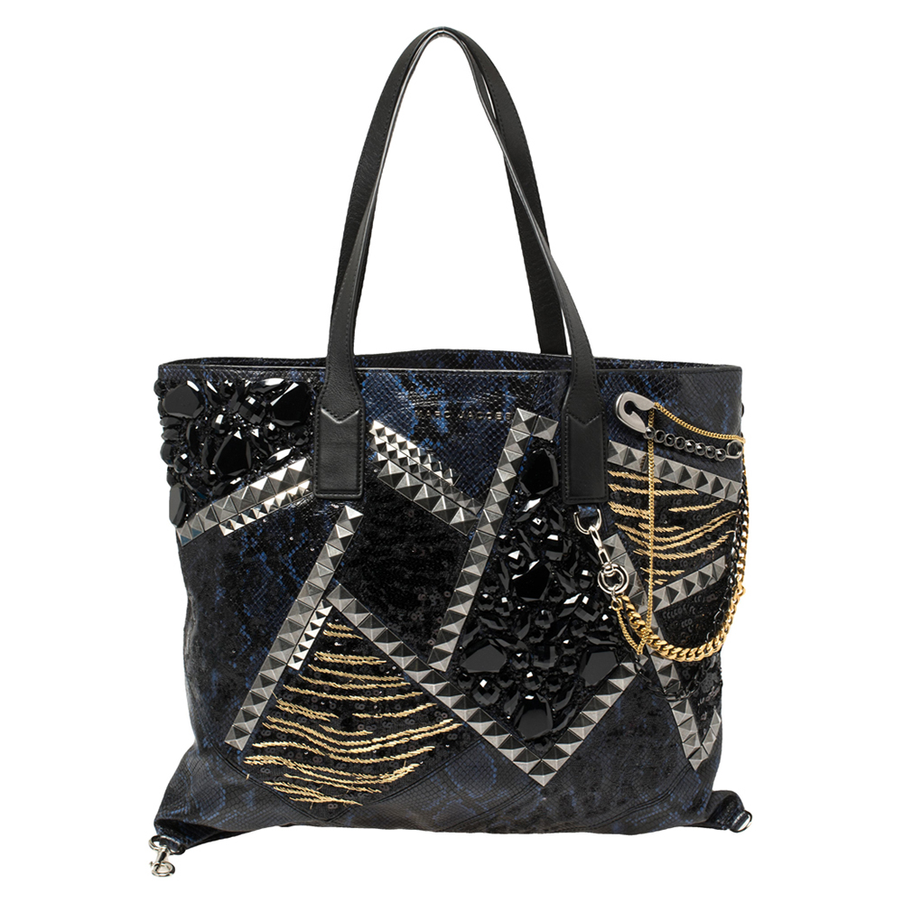 This one of a kind tote bag by Marc Jacobs is made for the one who loves high end luxury and stylish creations. Crafted from python embossed leather the exterior is embellished with studs chains and sequins for a rock chic vibe. The interior is spacious that makes it a fashion meets function accessory.