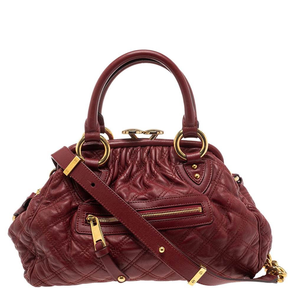 This Marc Jacobs design has a red quilted exterior crafted from leather and enhanced with gold tone hardware. This elegant Stam bag features a kiss lock top closure that opens to a fabric interior dual top handles and a removable chain that converts this piece between shoulder and hand styles easily. Swing this beauty wherever you go and make heads turn