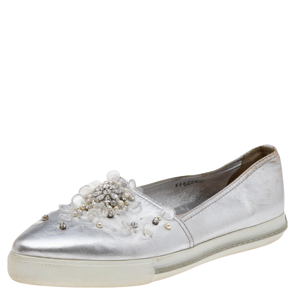 How gorgeous are these sneakers from the House of Miu Miu Crafted from metallic silver leather these slip on sneakers flaunt intricate crystal embellishments on the vamps and pointed toes. Charming and comfortable these Miu Miu sneakers are an ideal pick for everyday use.