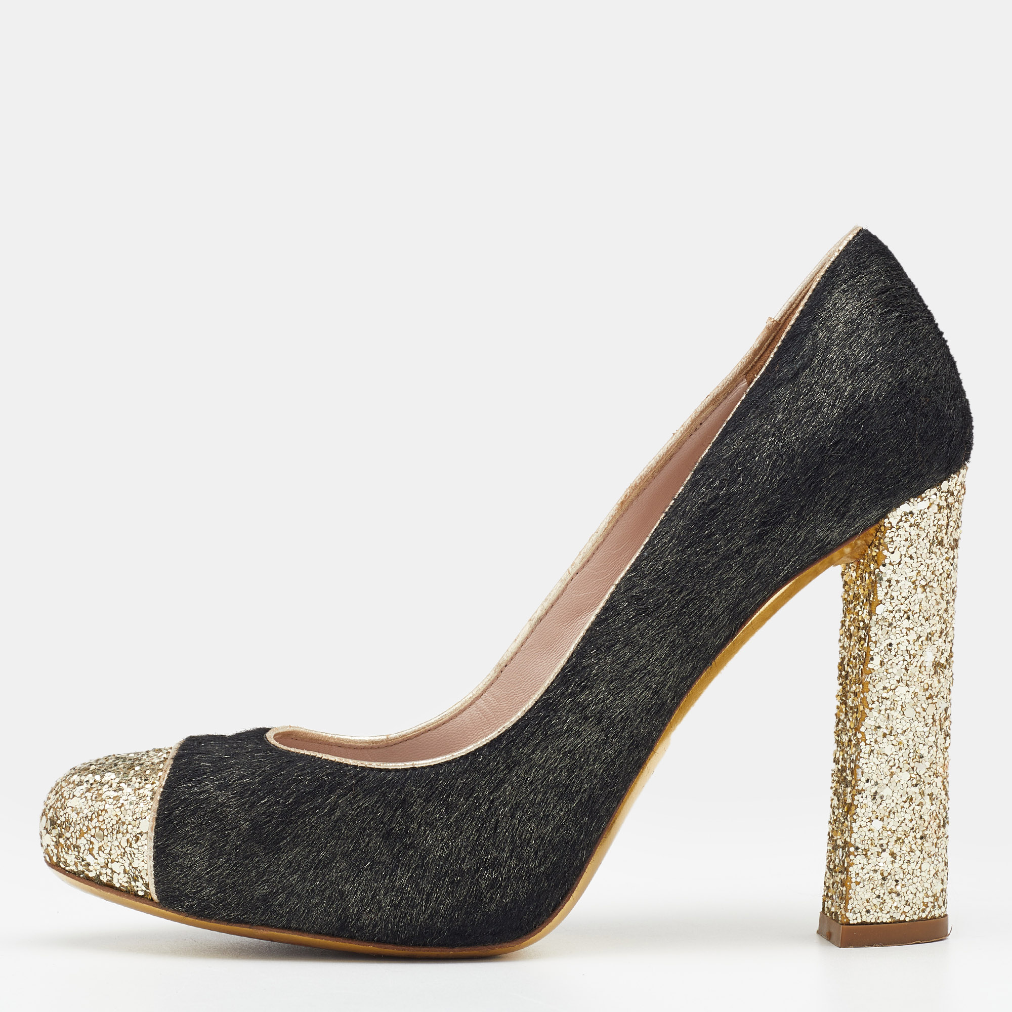 Grab these gorgeous pumps from the House of Miu Miu and walk confidently with elegant grace Fashioned in black gold calf hair and glitter these pumps are enhanced with cap toes block heels and a slip on feature. These pumps will pair well with your party outfits.