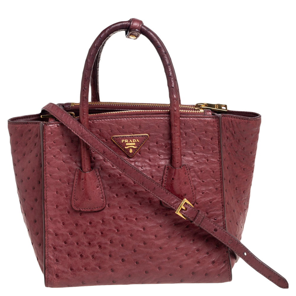 Add timeless style and luxury to your look with this stunning Prada Twin tote. Crafted in red ostrich leather this bag can store all that you need in its spacious interior. The tote is detailed with the brand logo on the front held by dual handles and protected by studs on the base.