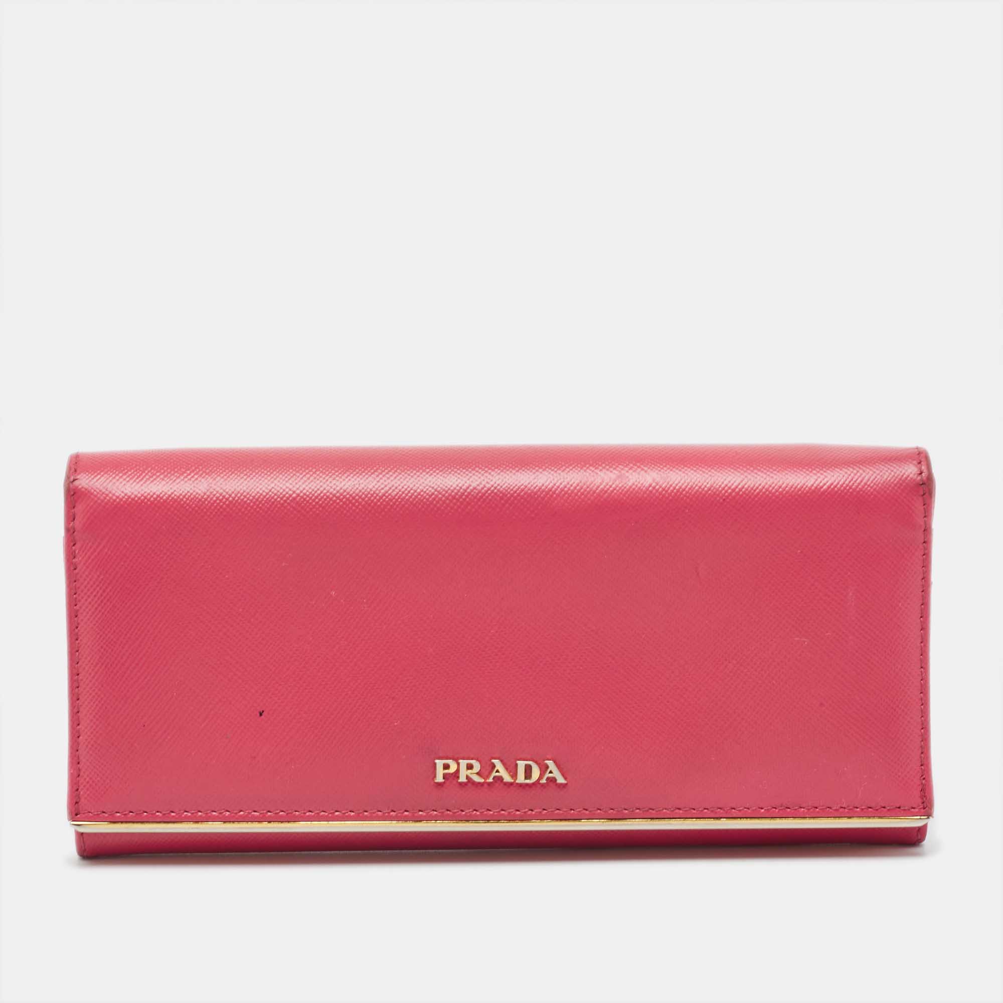A sophisticated wallet crafted in blush pink Saffiano leather is the season's new style statement. This continental flap wallet by Prada features metal detailing. The front flap closure opens to a leather and fabric lined interior and has card slots and a compartment.