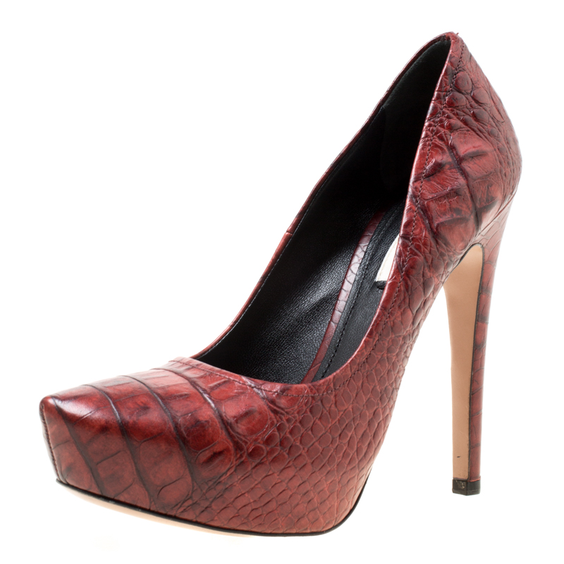 Create a dreamy look by twinning your outfit with this pair of Prada pumps. These maroon pumps are crafted from croc embossed leather and feature almond toes. They come equipped with comfortable insoles 13 cm heels and concealed platforms that offer maximum grip while walking. Grab them right away