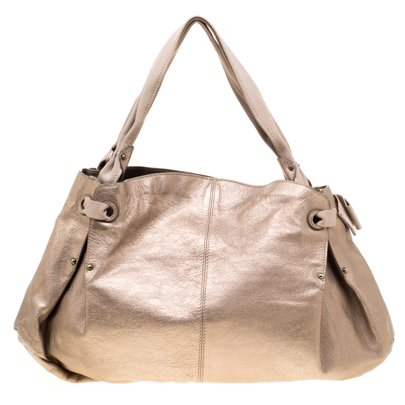This Salvatore Ferragamo hobo bag has a relaxed shape and it comes in beige. The bag is created from leather and detailed with a bow two handles and a spacious canvas interior for your essentials. It is gorgeous and ideal for daily use.