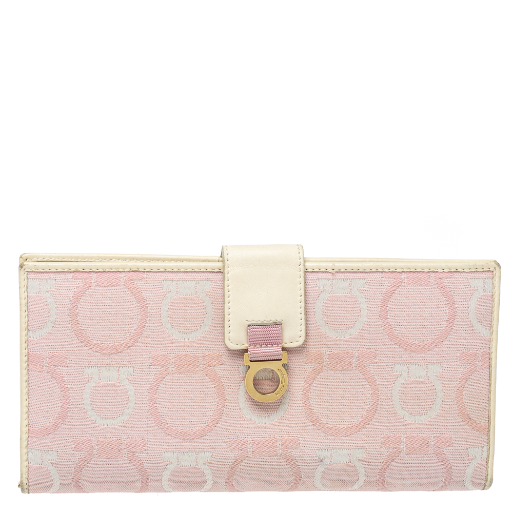 This stylish pink and cream creation from Salvatore Ferragamo is undoubtedly a fashionistas choice Crafted in high quality Gancini canvas and leather this wallet features a flap with the brand logo. It is complete with multiple slots and enough space to neatly organize your essentials.
