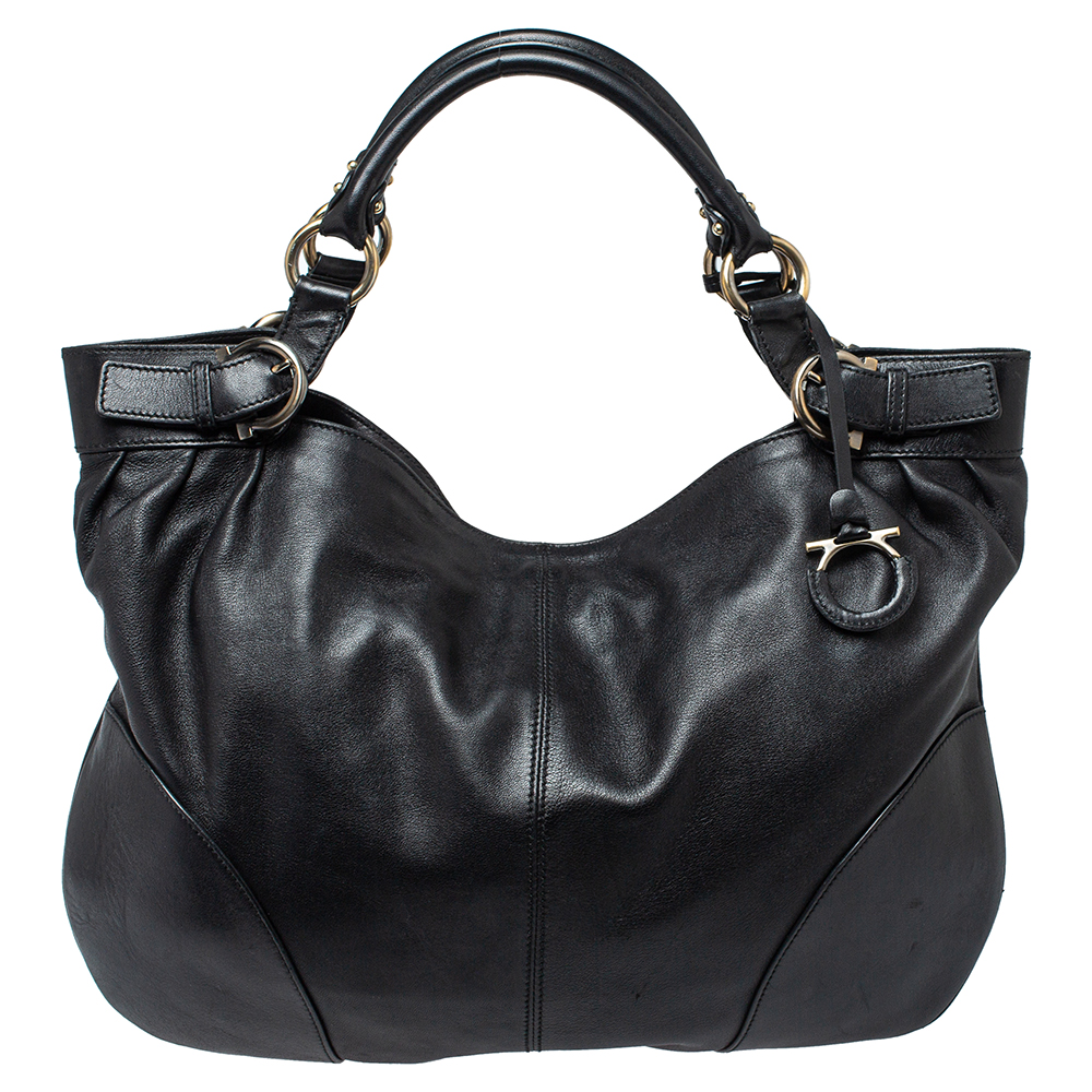 This Ferragamo tote makes an ultimate style statement for all the trend savvy women out there. It is crafted from black leather and styled with buckle detailed dual top handles. It opens to a fabric interior that has ample space to accommodate your daily essentials and is complete with an attached ganchini logo charm.